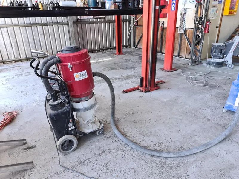 A Vacuum Cleaner is Sitting in a Garage Next to a Lift — Alan Aldridge Floor Sanding in Urraween, QLD