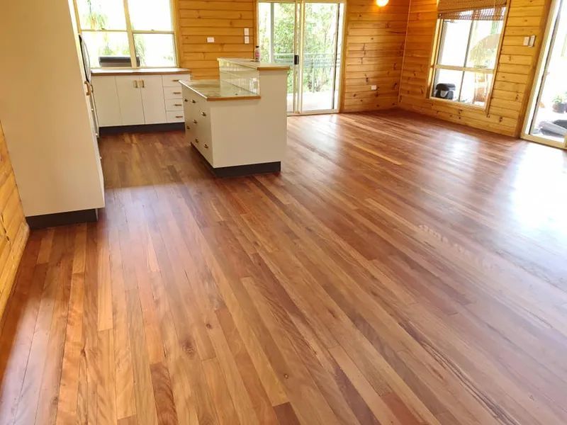 A Kitchen With a Wooden Floor and White Cabinets — Alan Aldridge Floor Sanding in Urraween, QLD