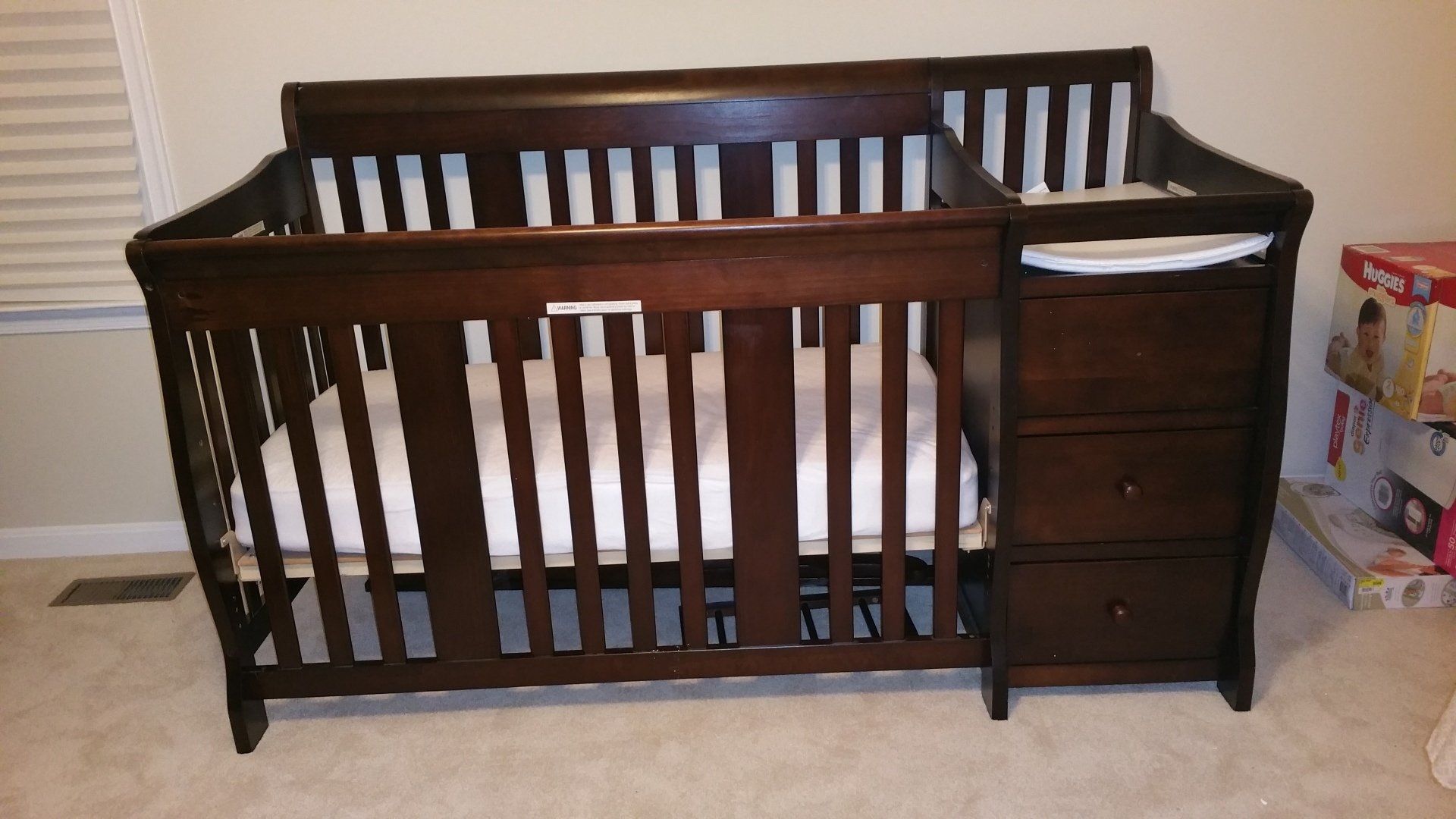 A baby crib with a changing table attached to it