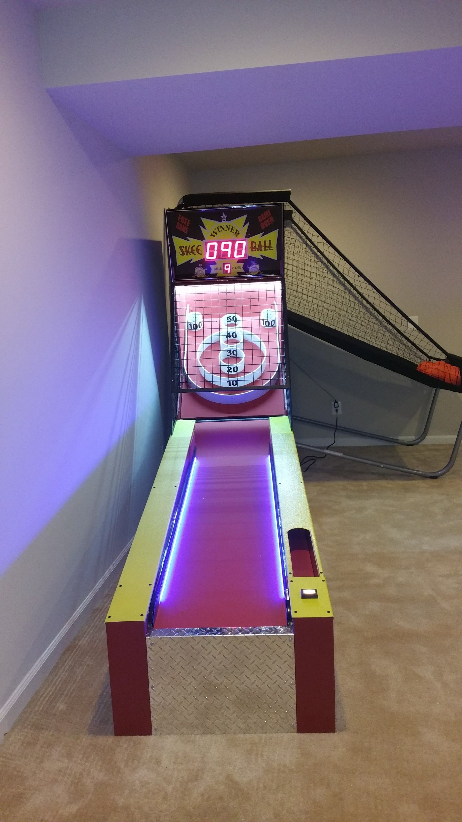 A basketball game is sitting in a room next to a basketball net.