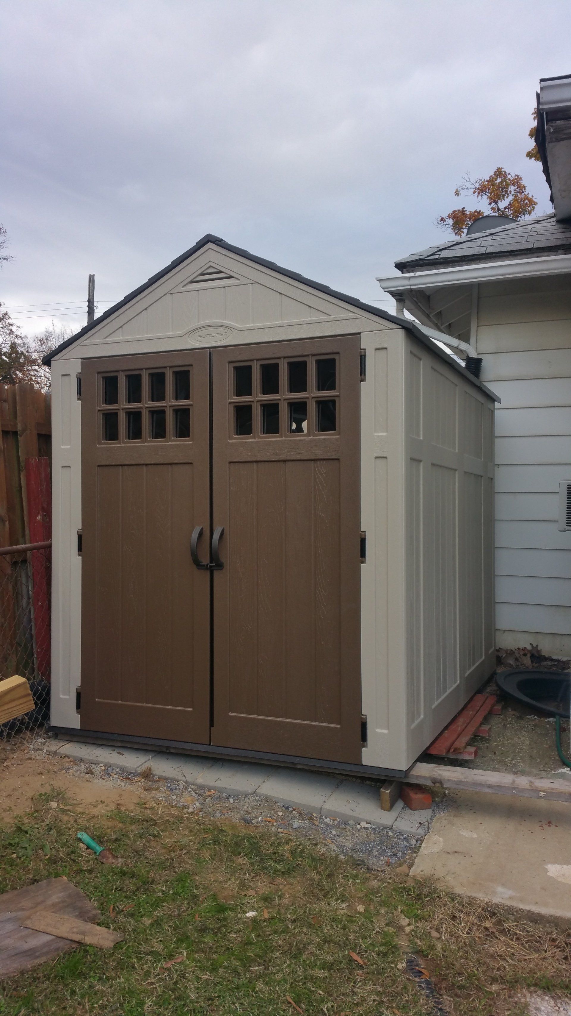 A brown and white shed is sitting next to a house.