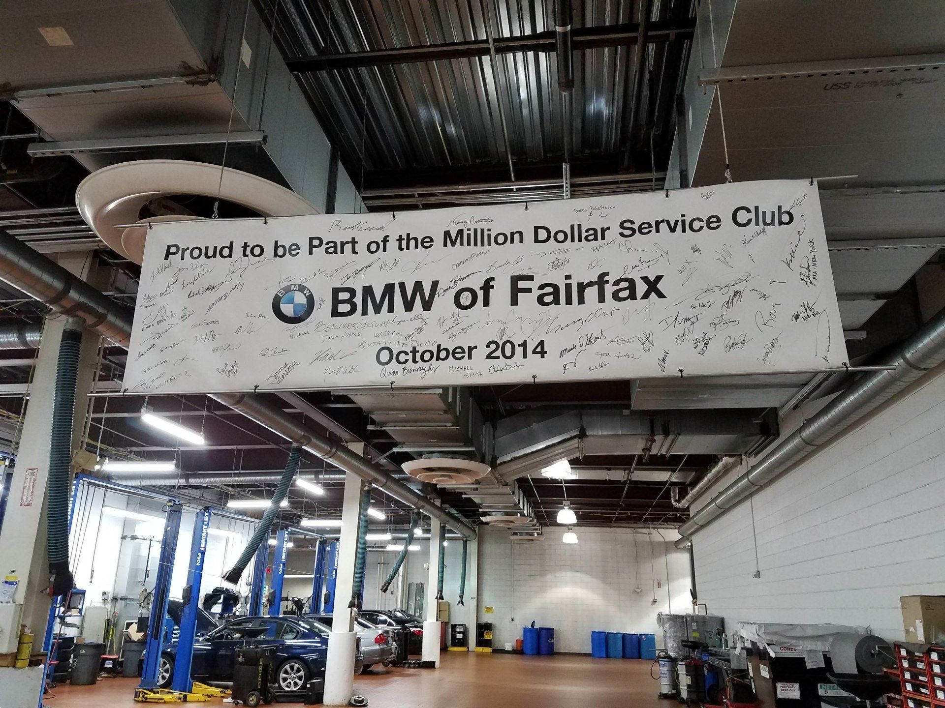 A bmw of fairfax sign hangs from the ceiling of a garage