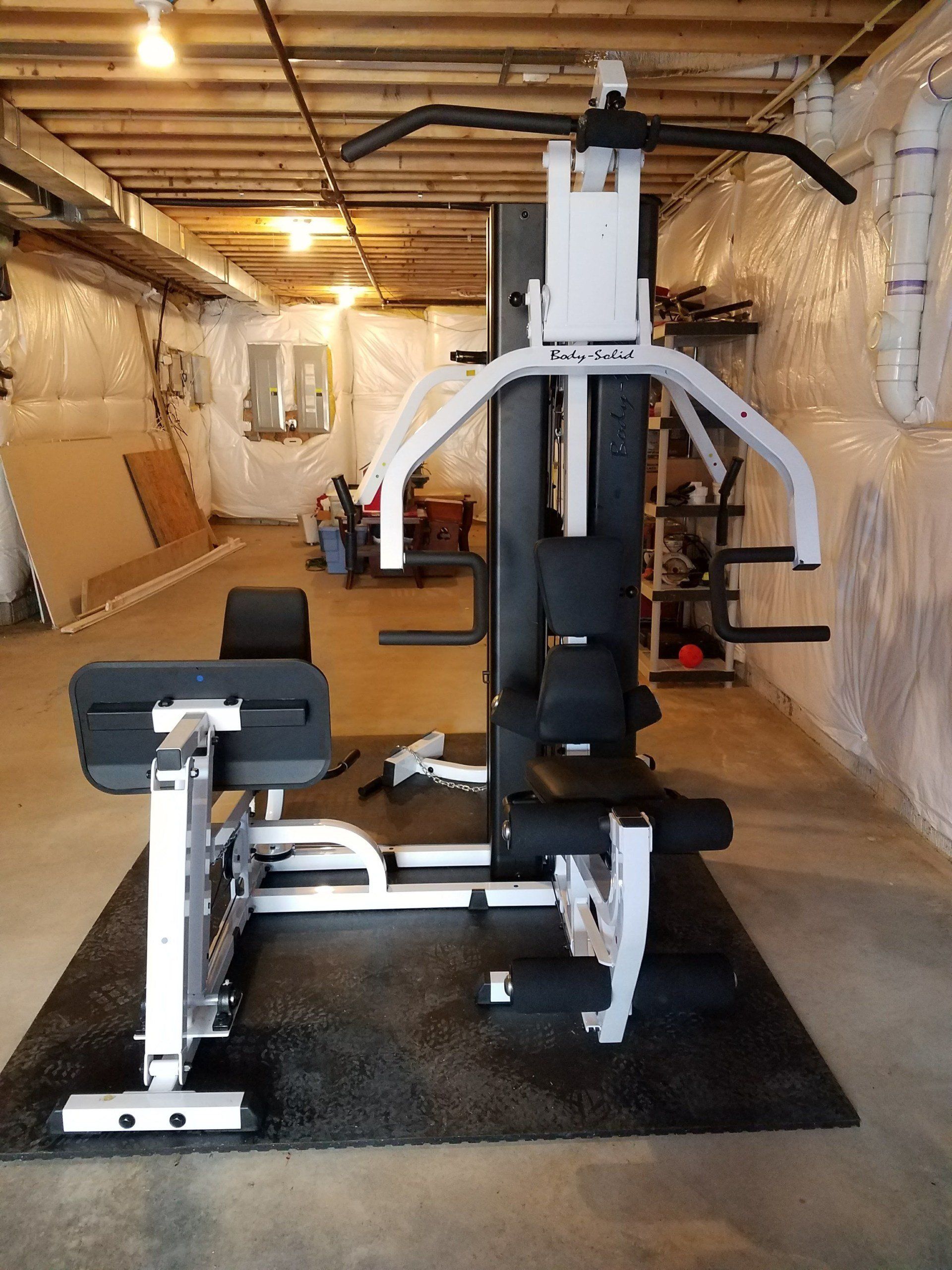 A gym machine is sitting on a mat in a basement