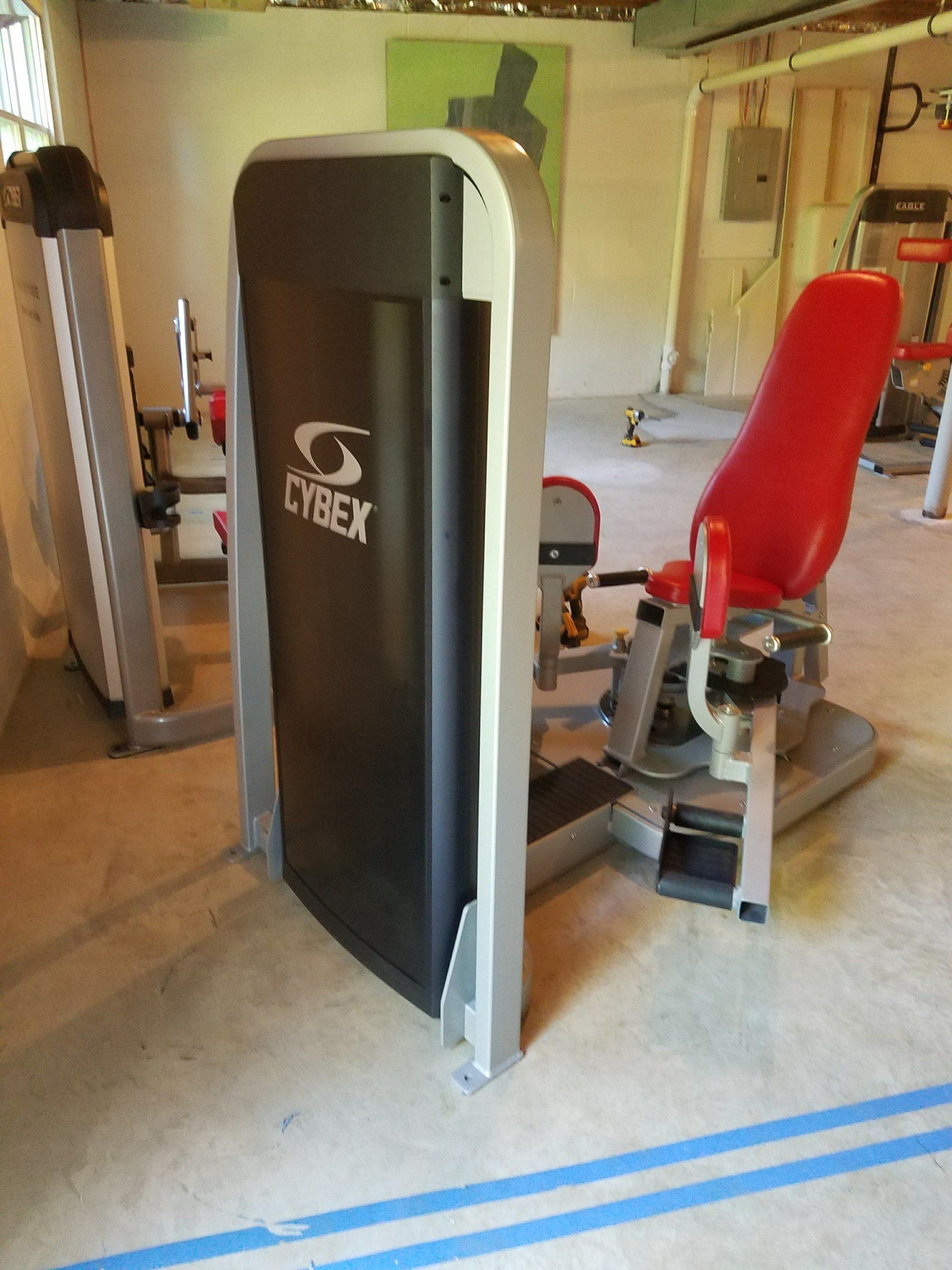 A gym with a cybex machine and a red chair