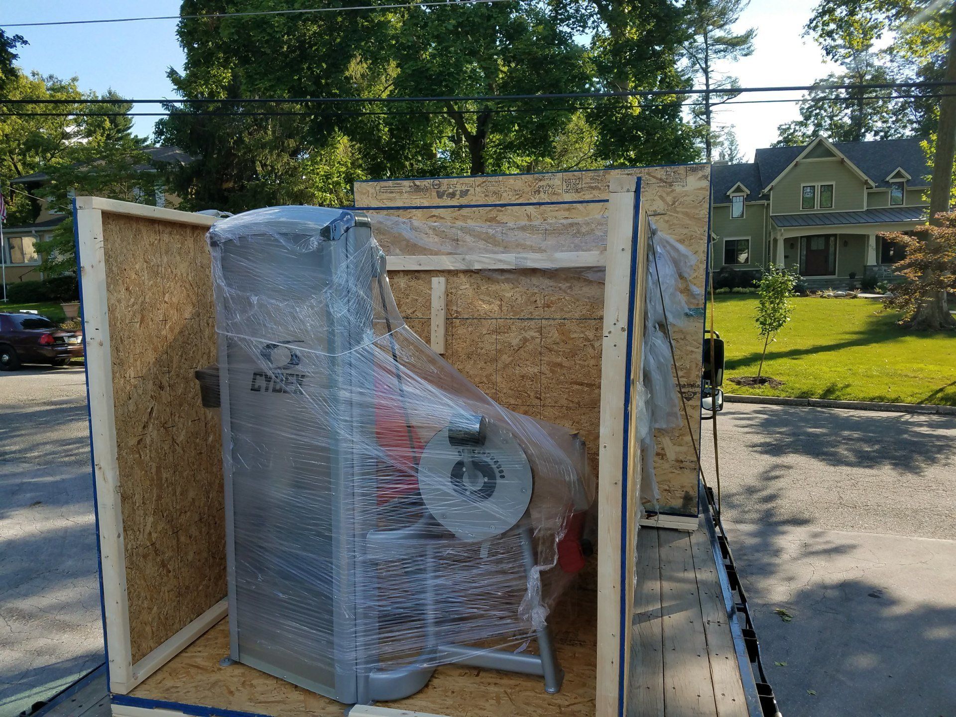 A machine is wrapped in plastic and sitting inside of a wooden crate.