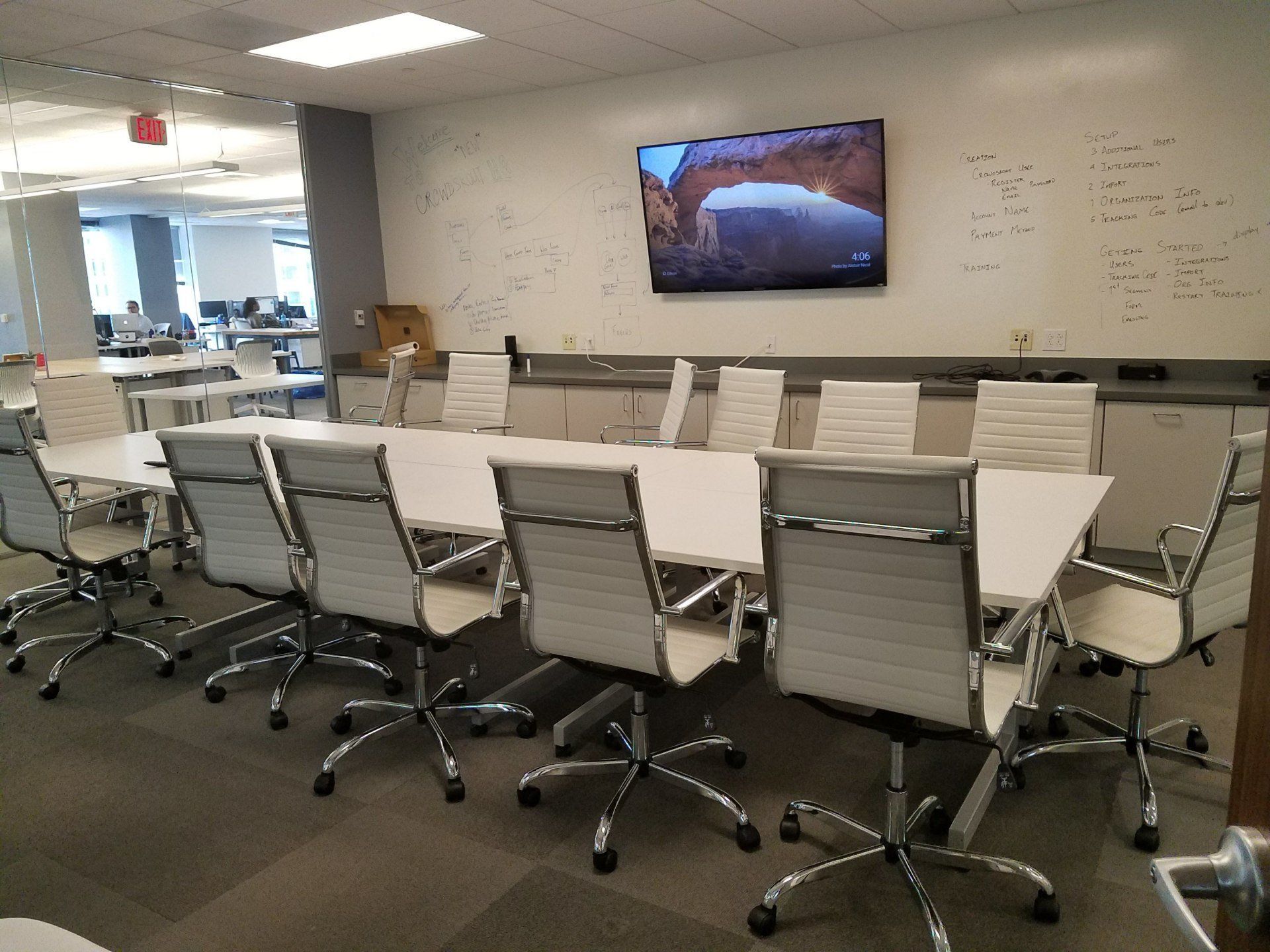 A conference room with a long table and chairs and a flat screen tv on the wall.