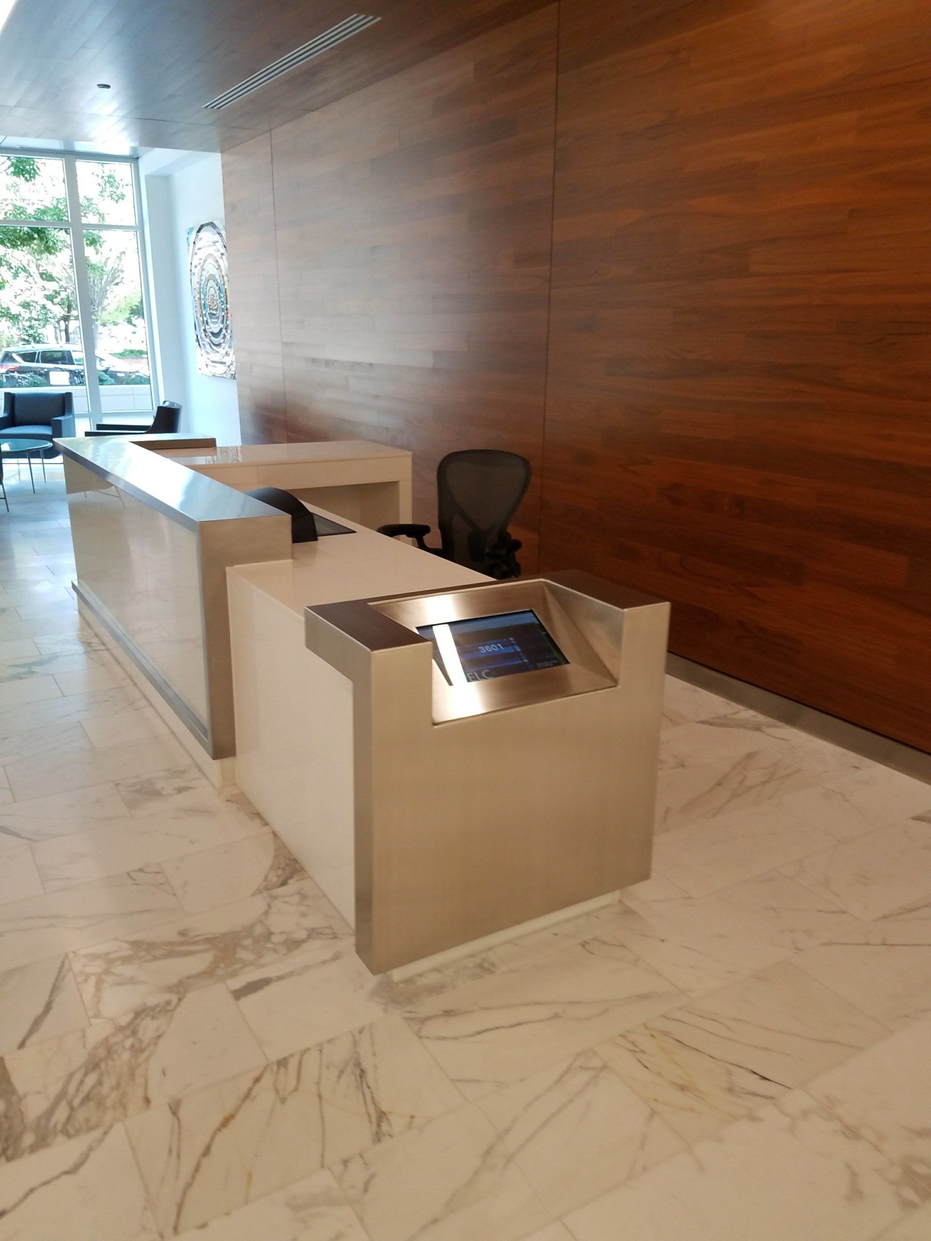 A stainless steel reception desk with a tablet on it in a lobby.