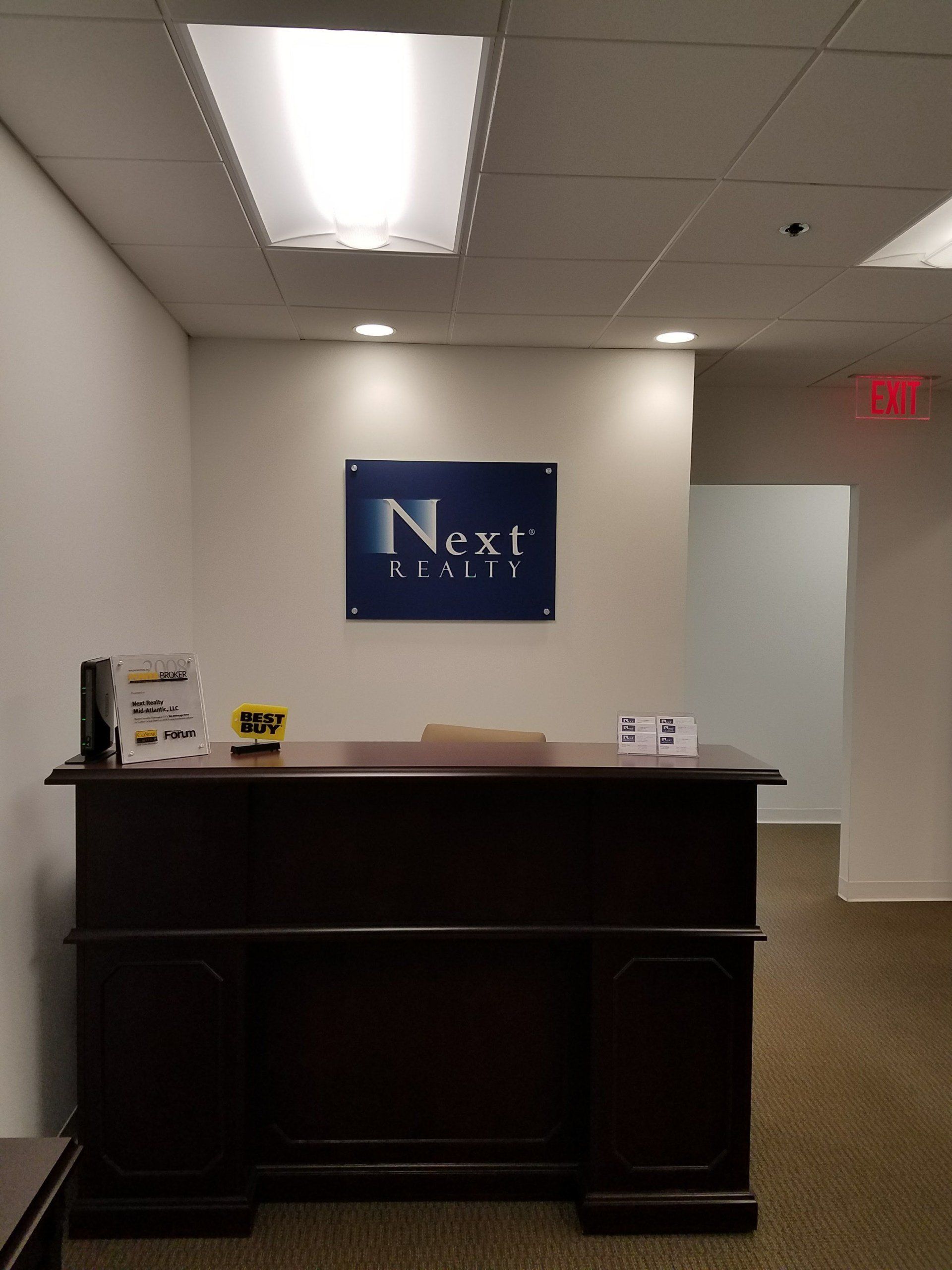 A reception desk with a sign above it that says next realty