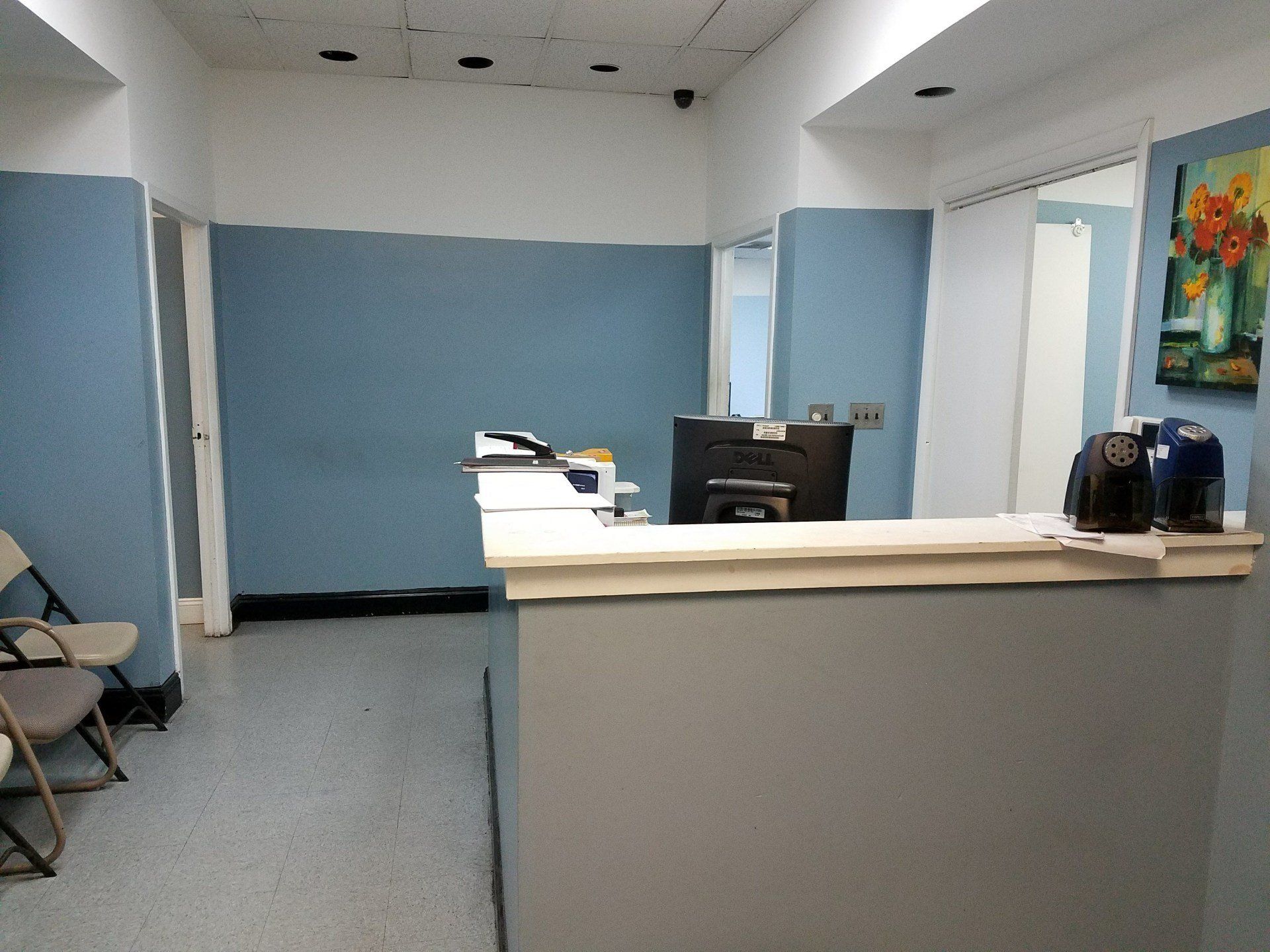 A waiting room with a desk and chairs and a painting on the wall
