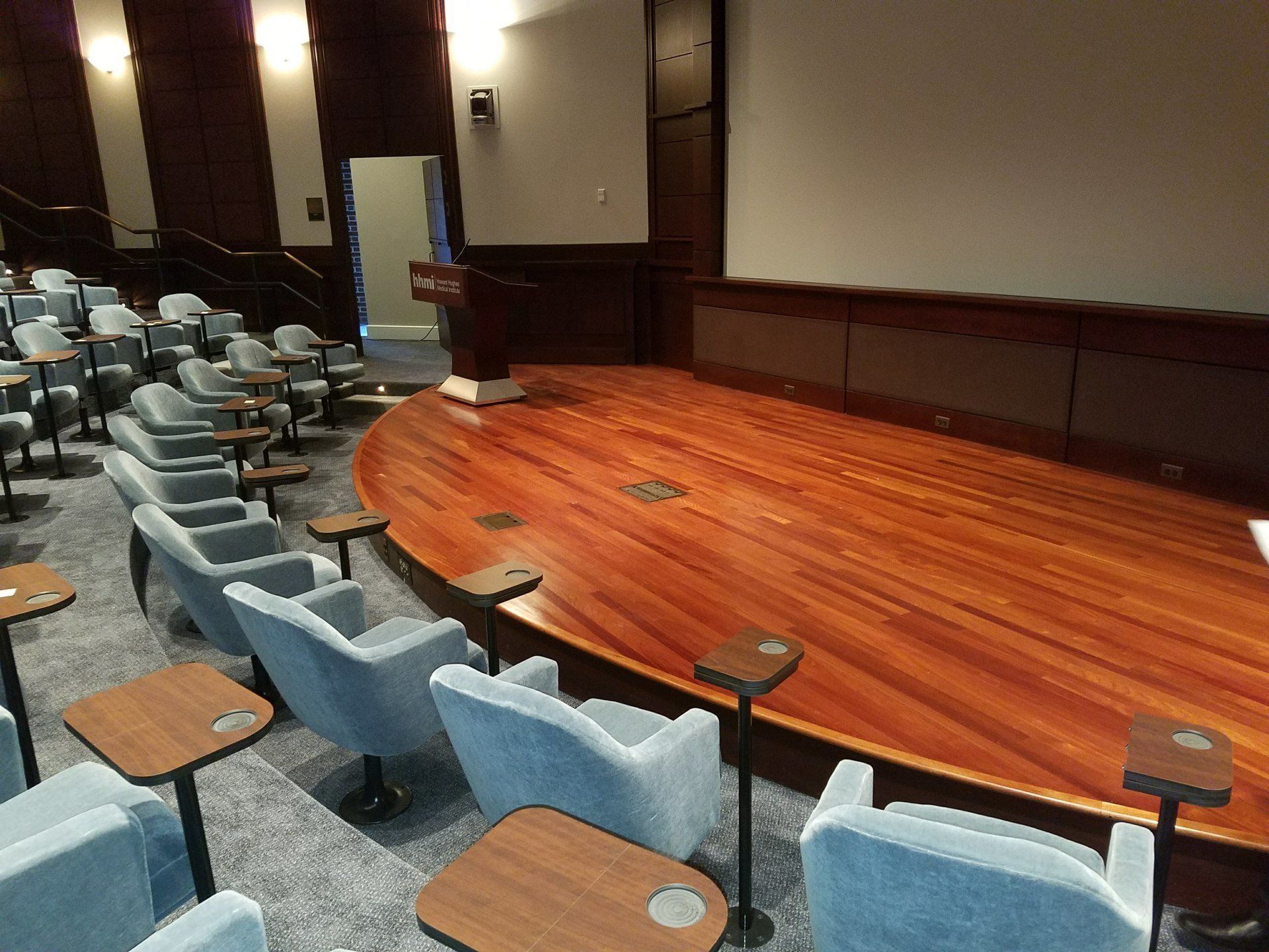 A large auditorium with a wooden stage and chairs
