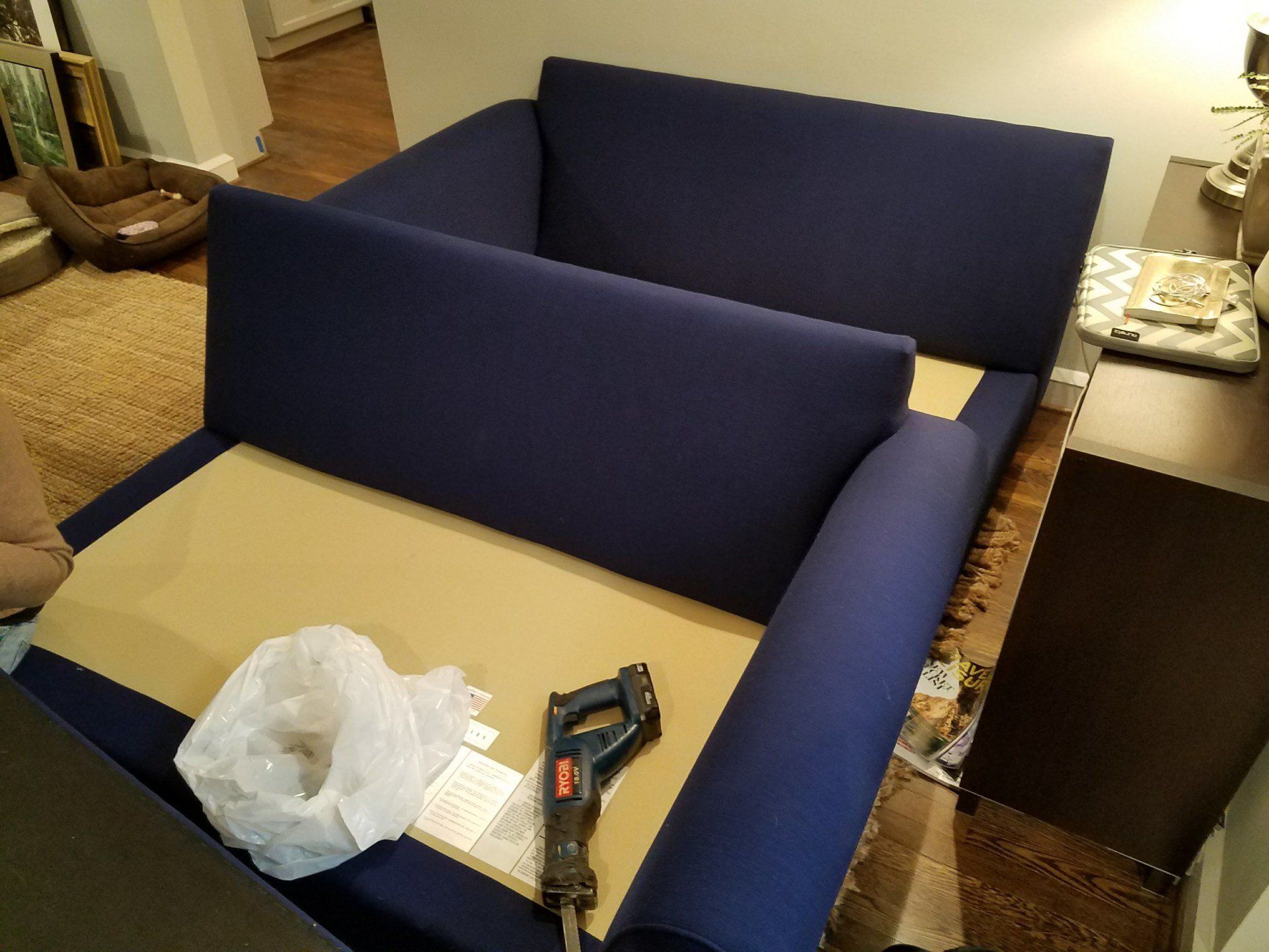 A blue couch is being built in a living room.