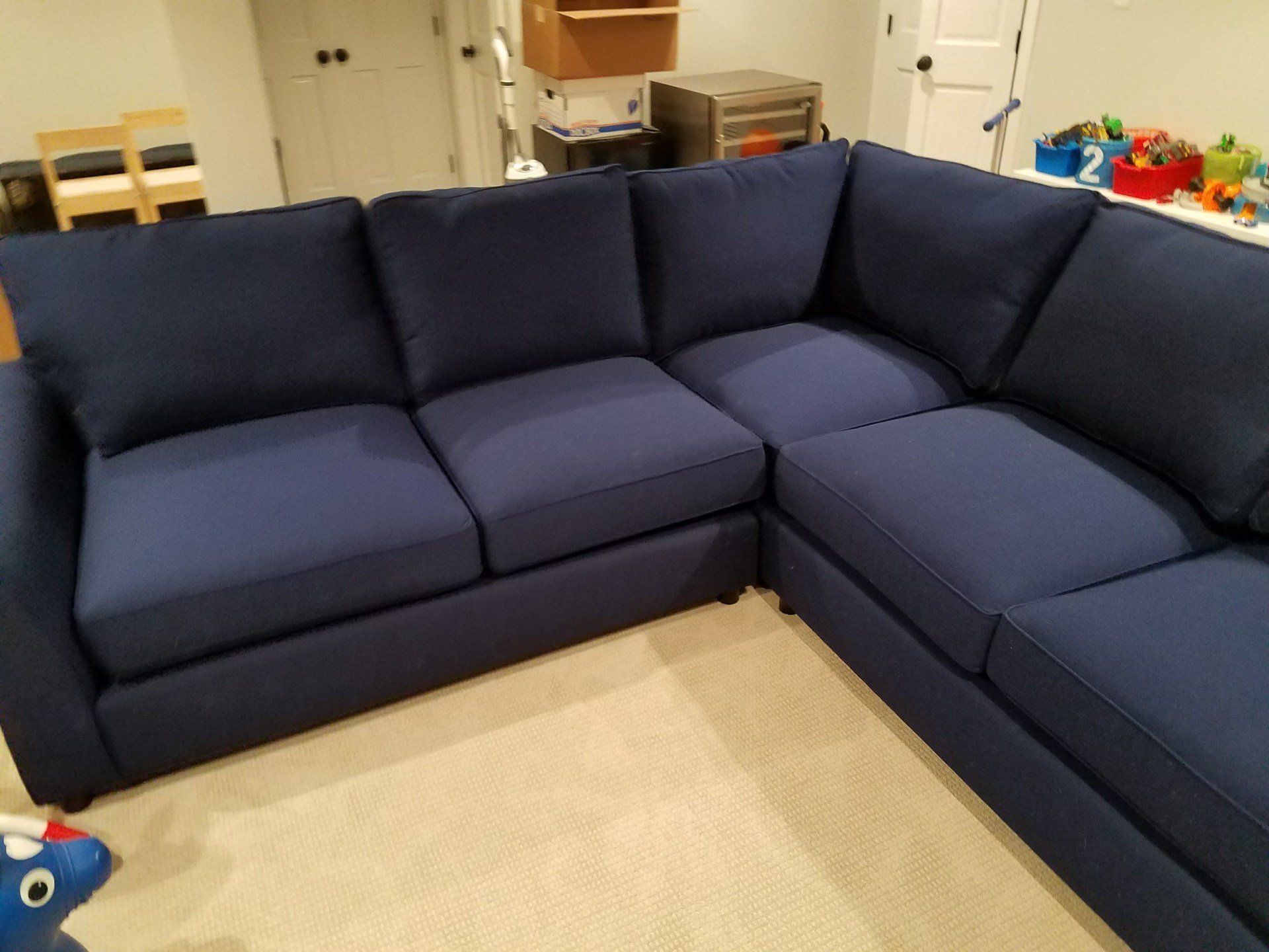 A blue sectional couch is sitting in a living room.