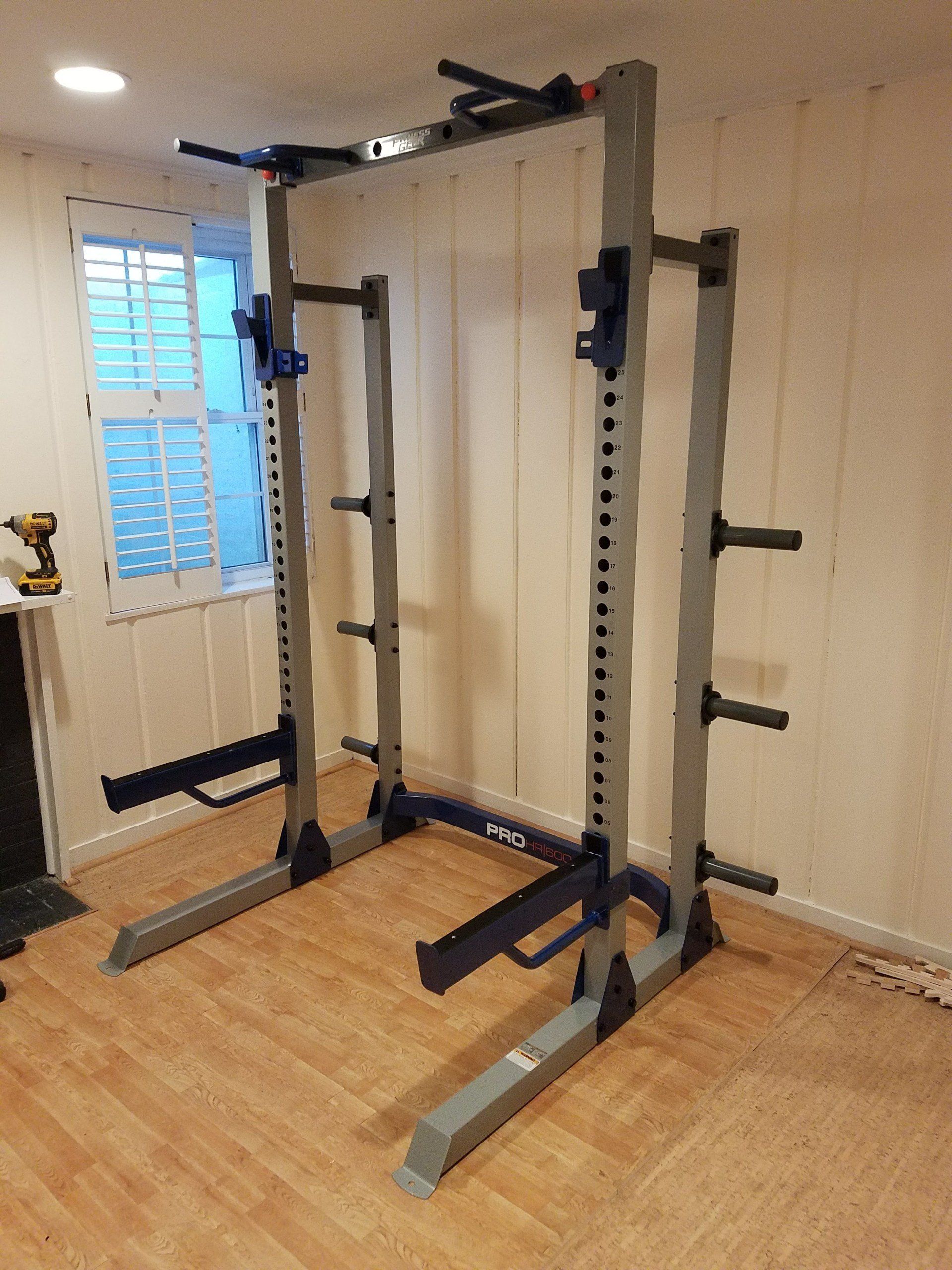 A squat rack is sitting in a room next to a window.