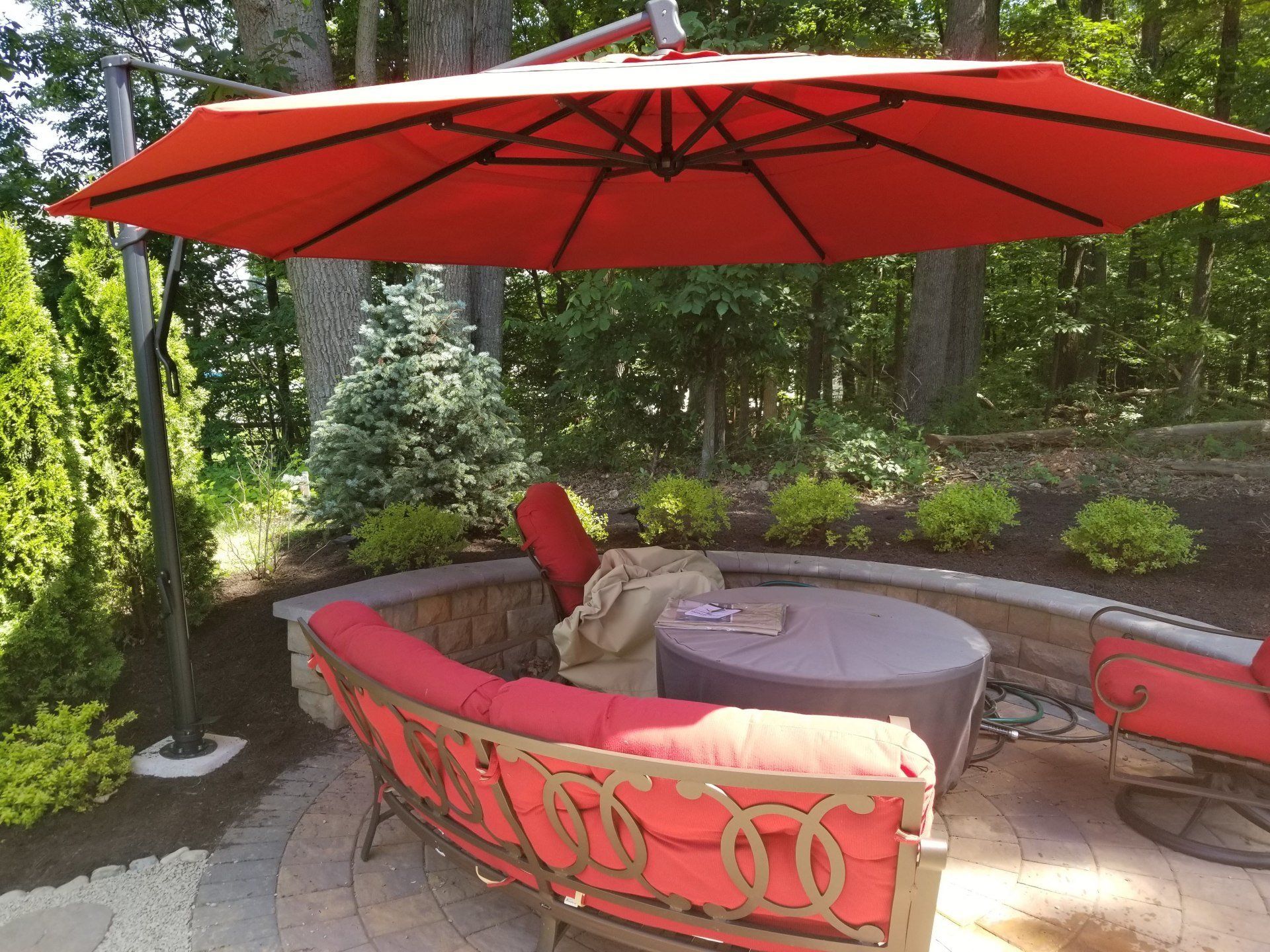 A red umbrella is sitting on top of a patio with furniture.