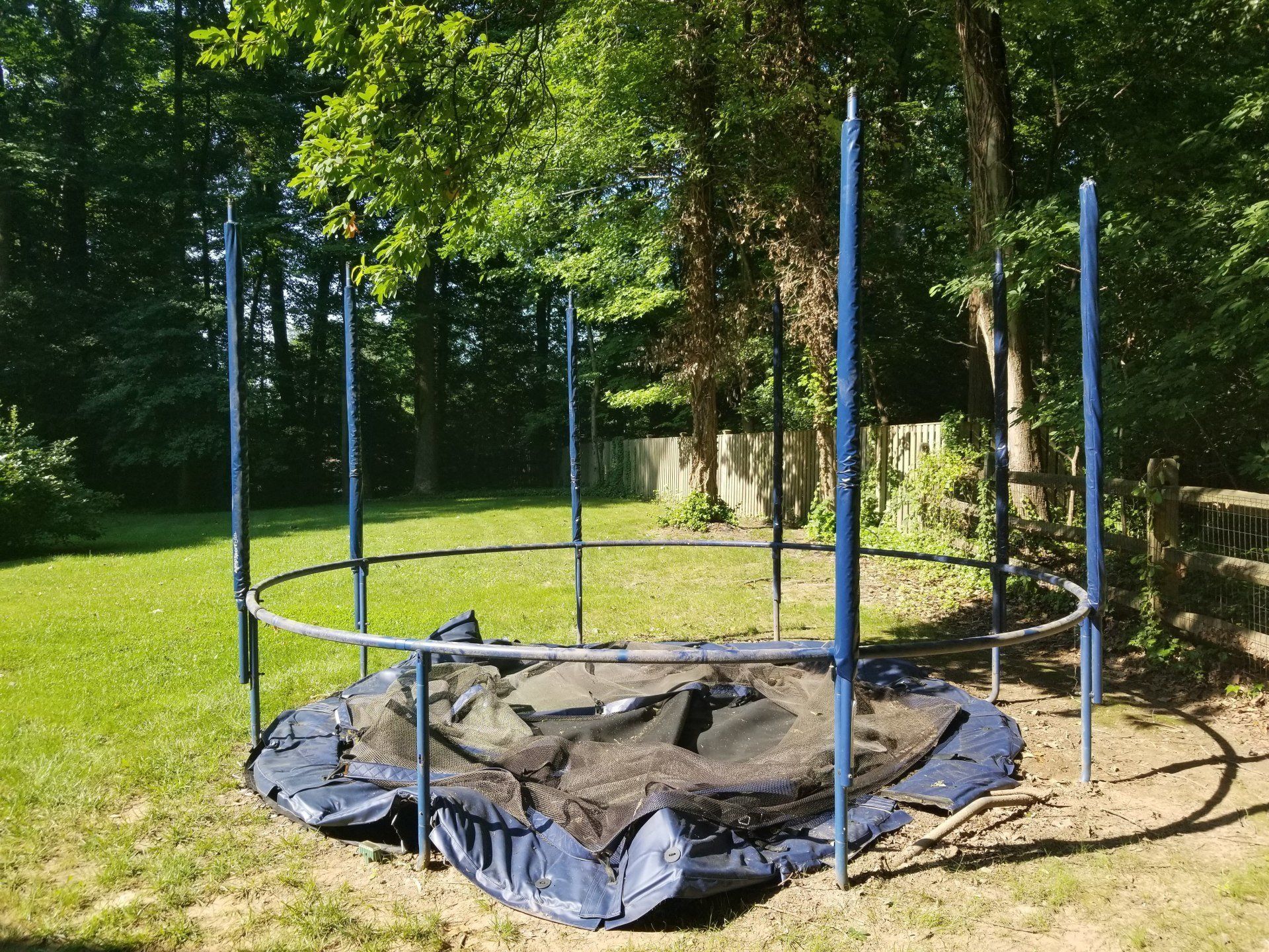 A trampoline is sitting in the middle of a lush green field.