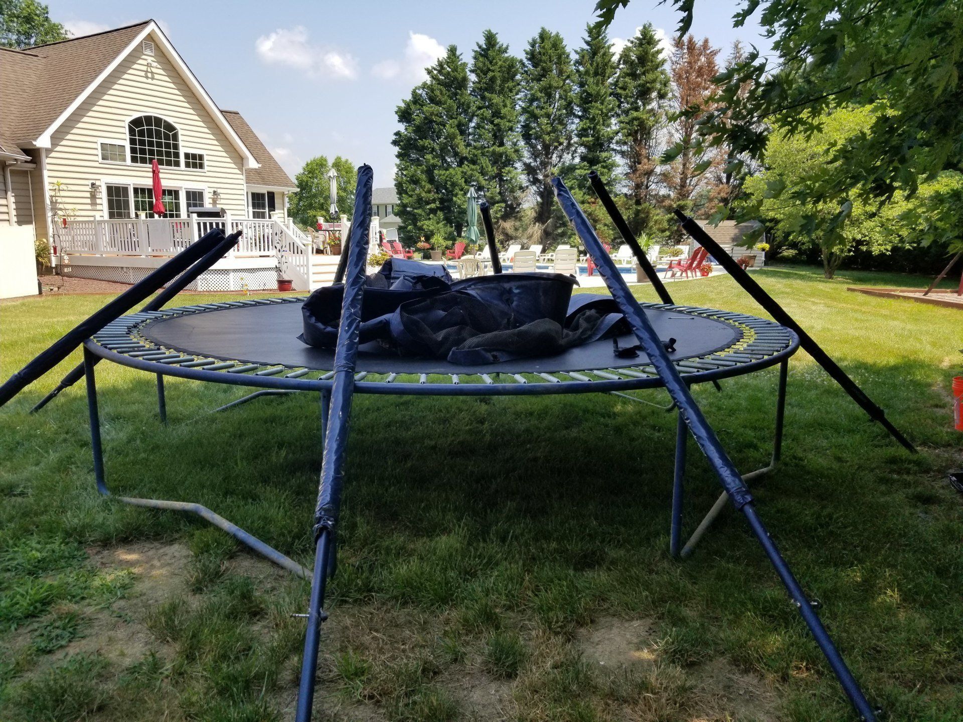 A trampoline is sitting in the grass in front of a house.
