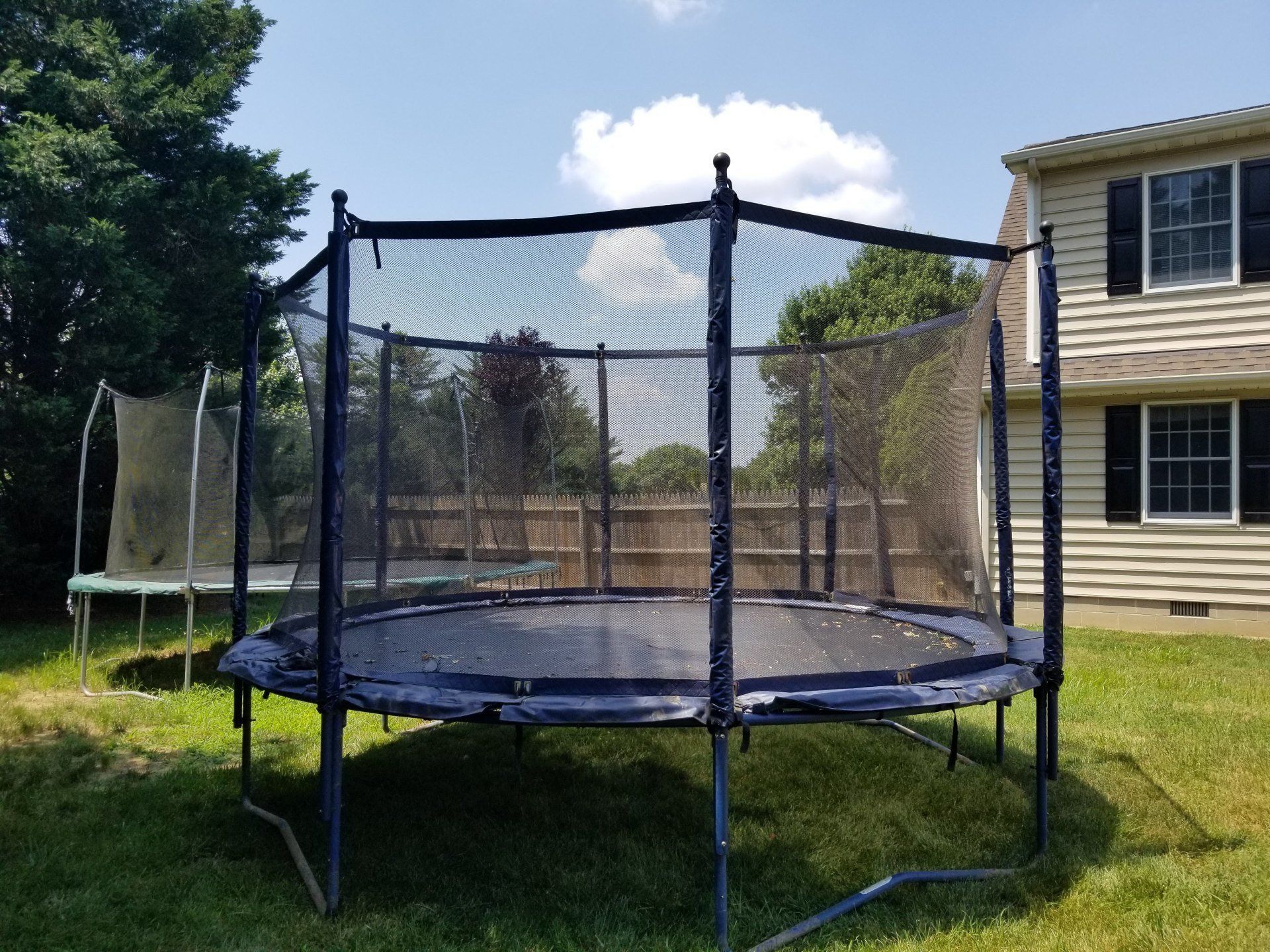 A trampoline is sitting in the grass in front of a house