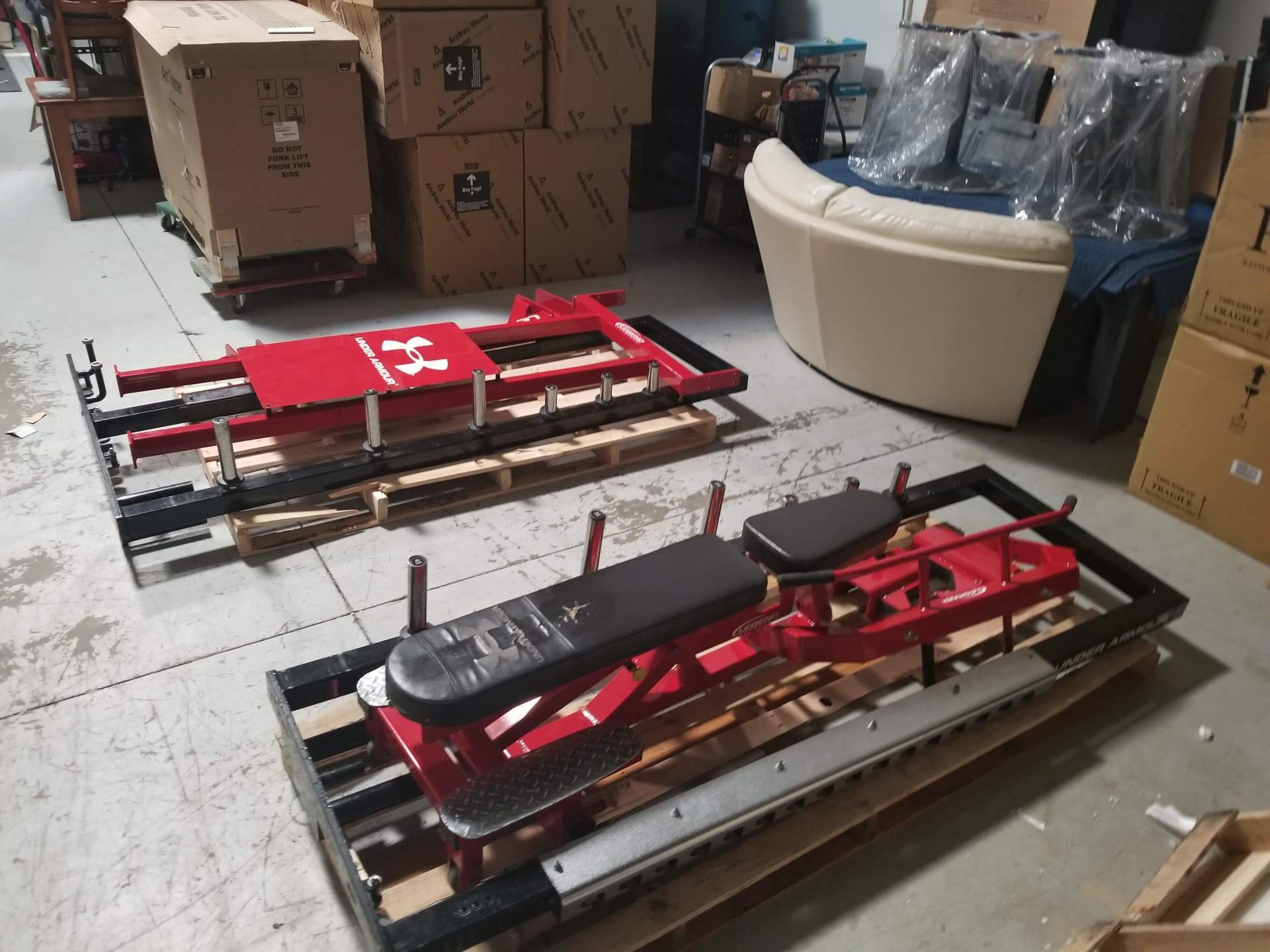 Two benches are sitting on pallets in a warehouse.