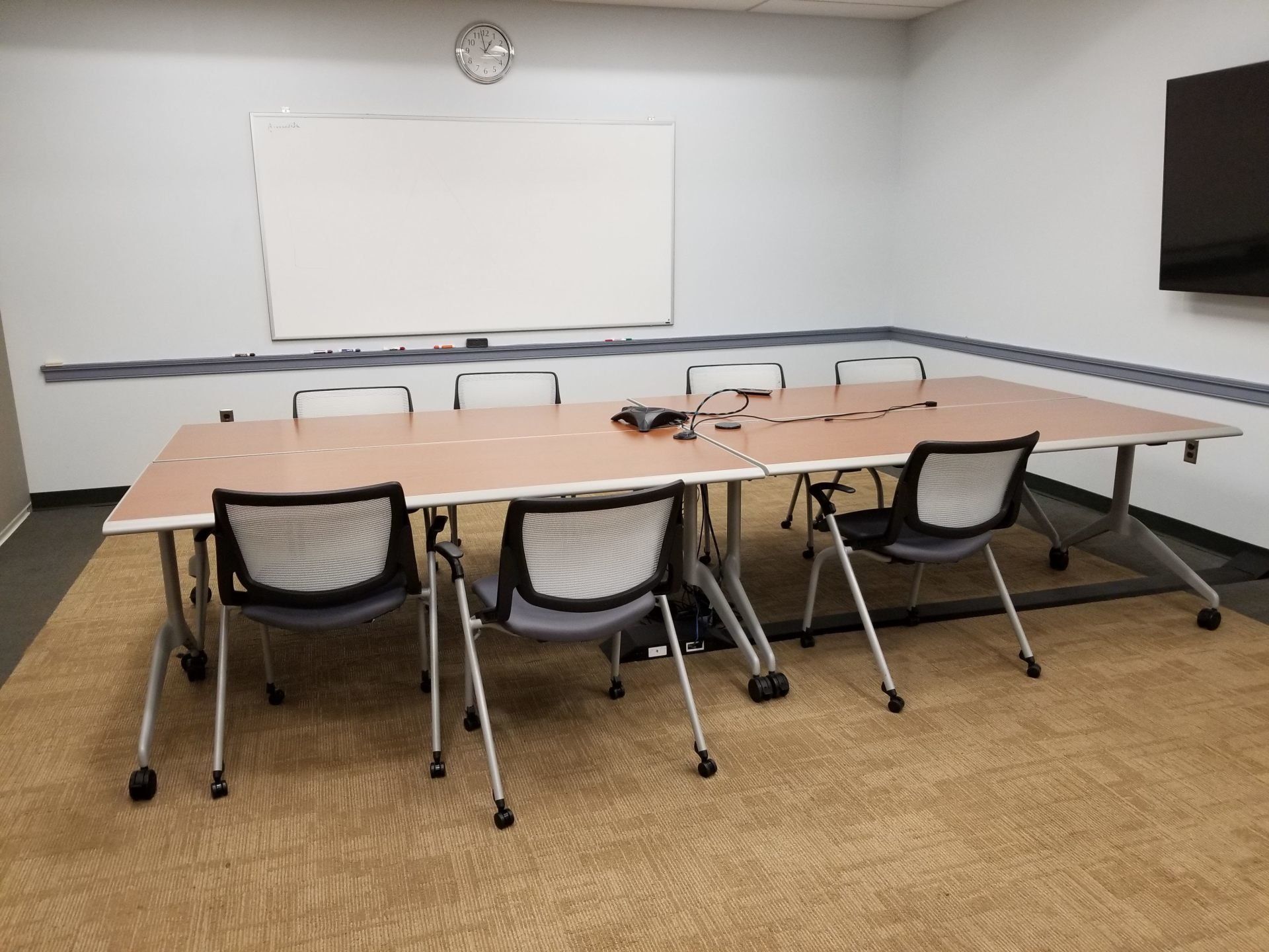 A conference room with a long table and chairs and a whiteboard.