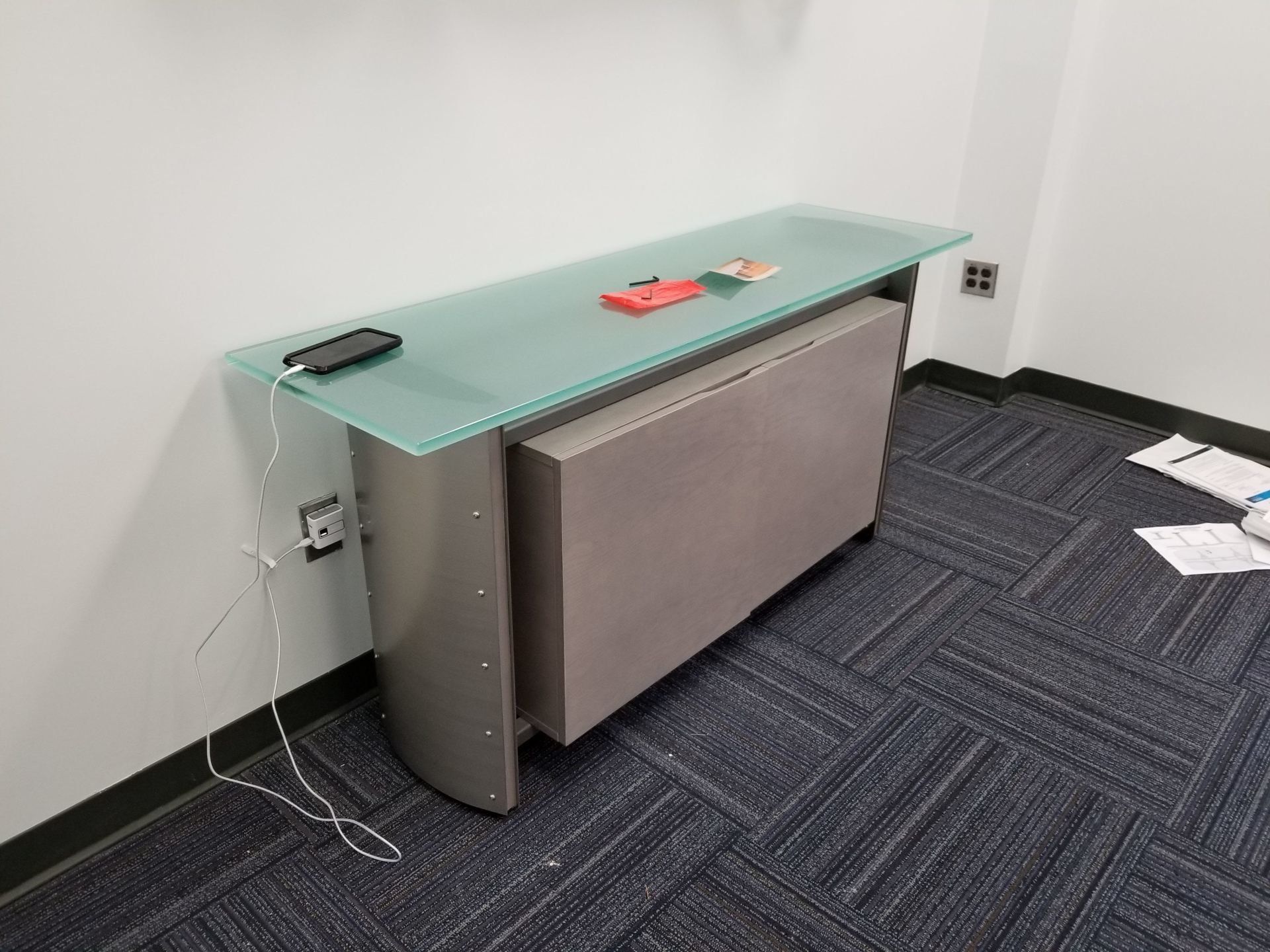 A long glass table with a phone on top of it in a room.