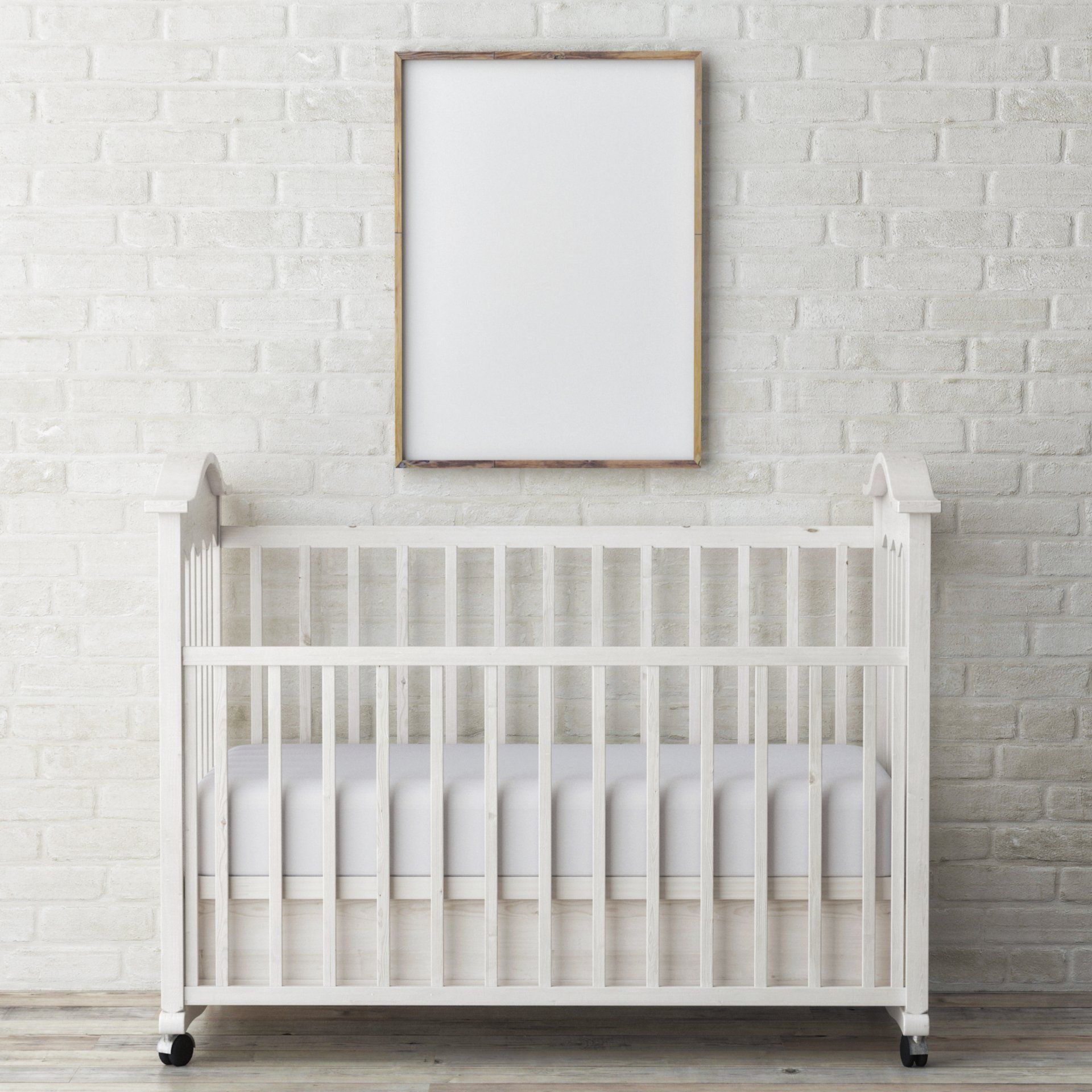 A white crib is sitting in front of a white brick wall.