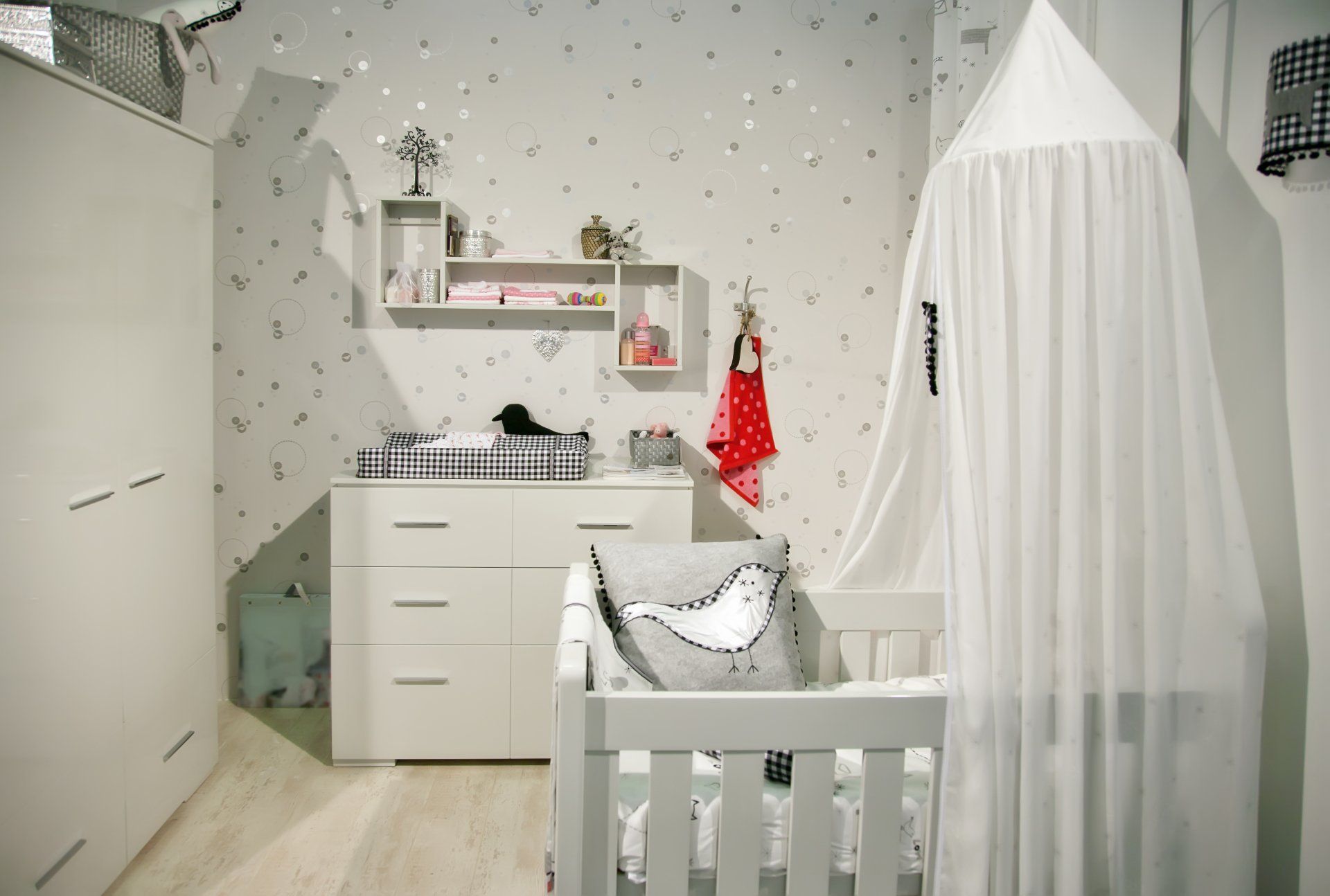 A baby 's room with a crib , changing table , and canopy.