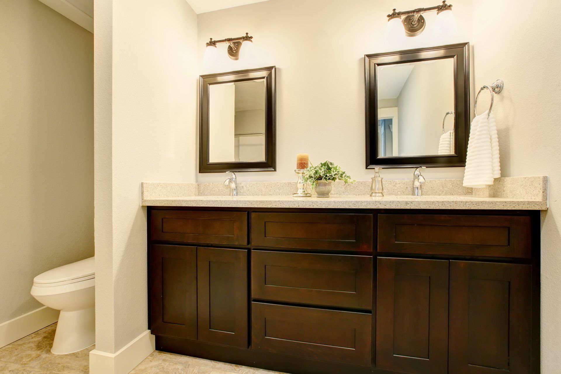 A bathroom with two sinks , two mirrors and a toilet.