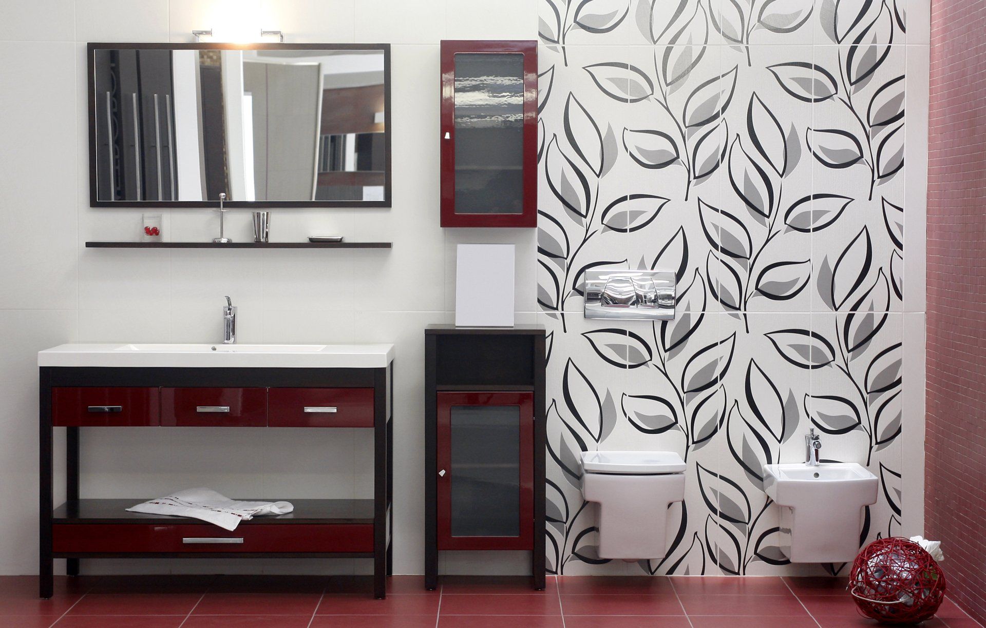 A bathroom with red tiles and black and white leaves on the wall