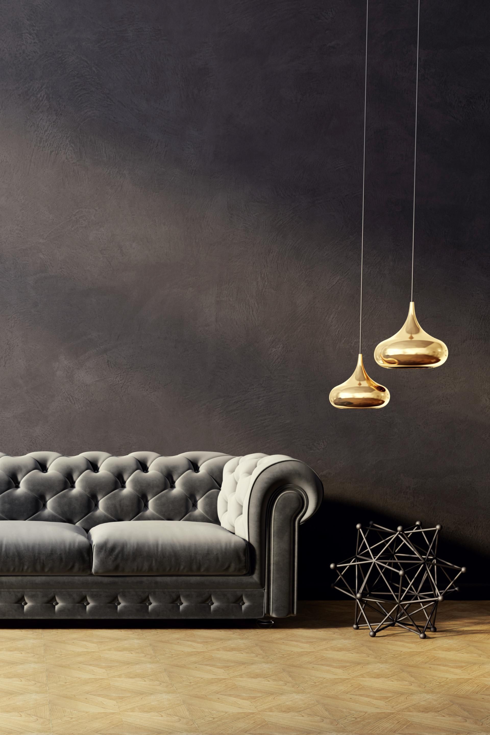 A living room with a couch and two pendant lights hanging from the ceiling.