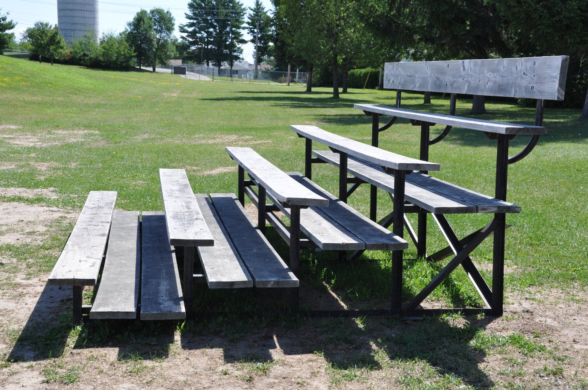 A row of wooden benches in a grassy field