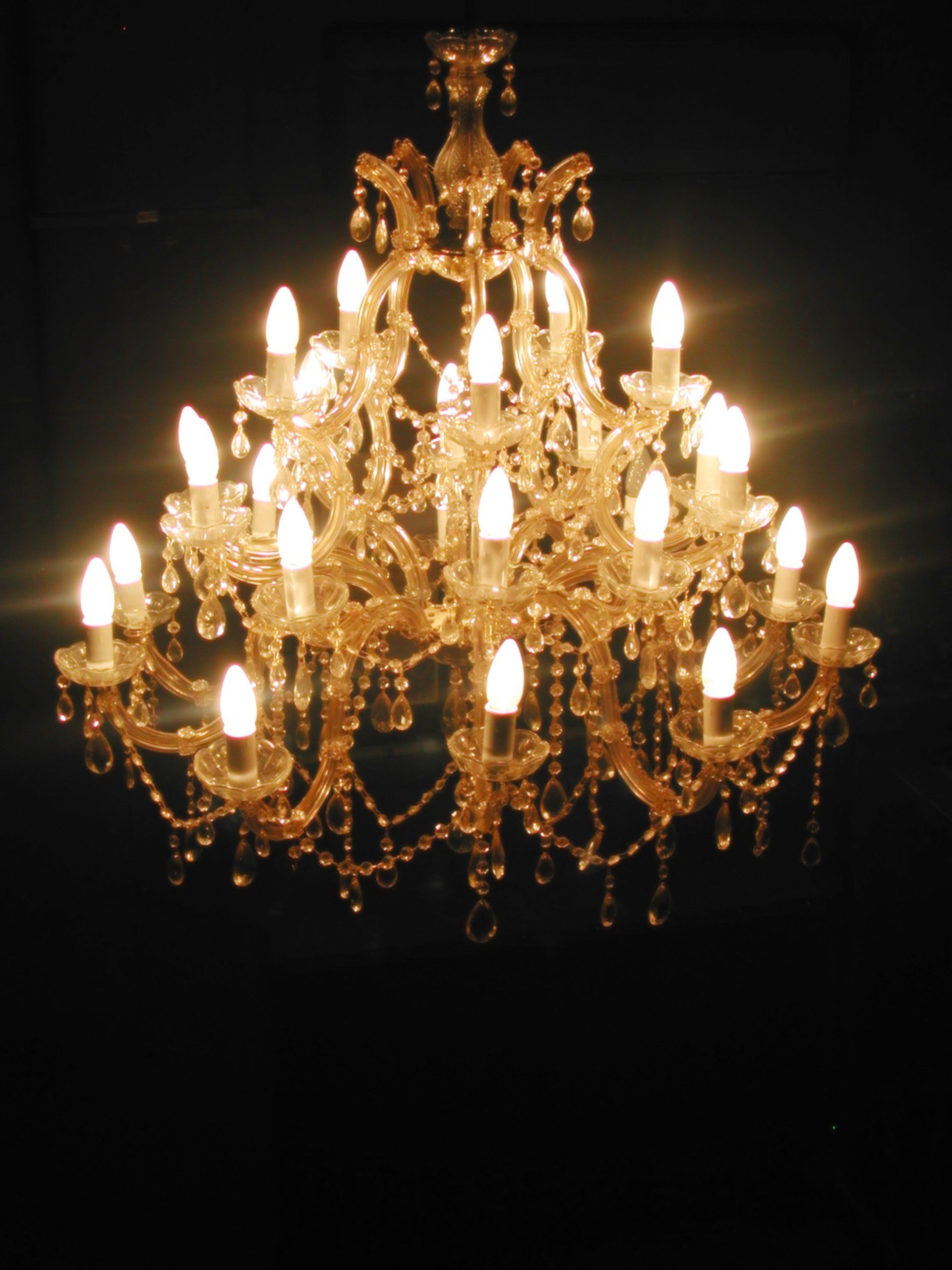 A chandelier is lit up in the dark with many candles