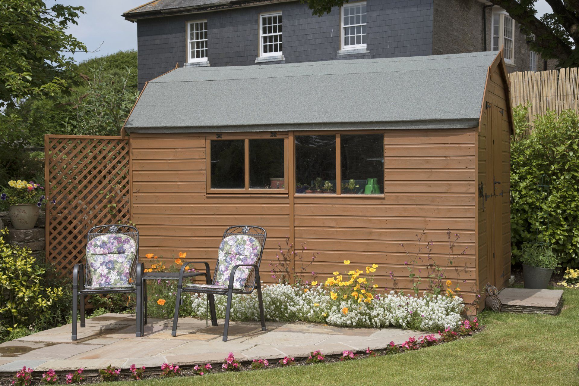 A wooden shed with chairs and a table in front of a house