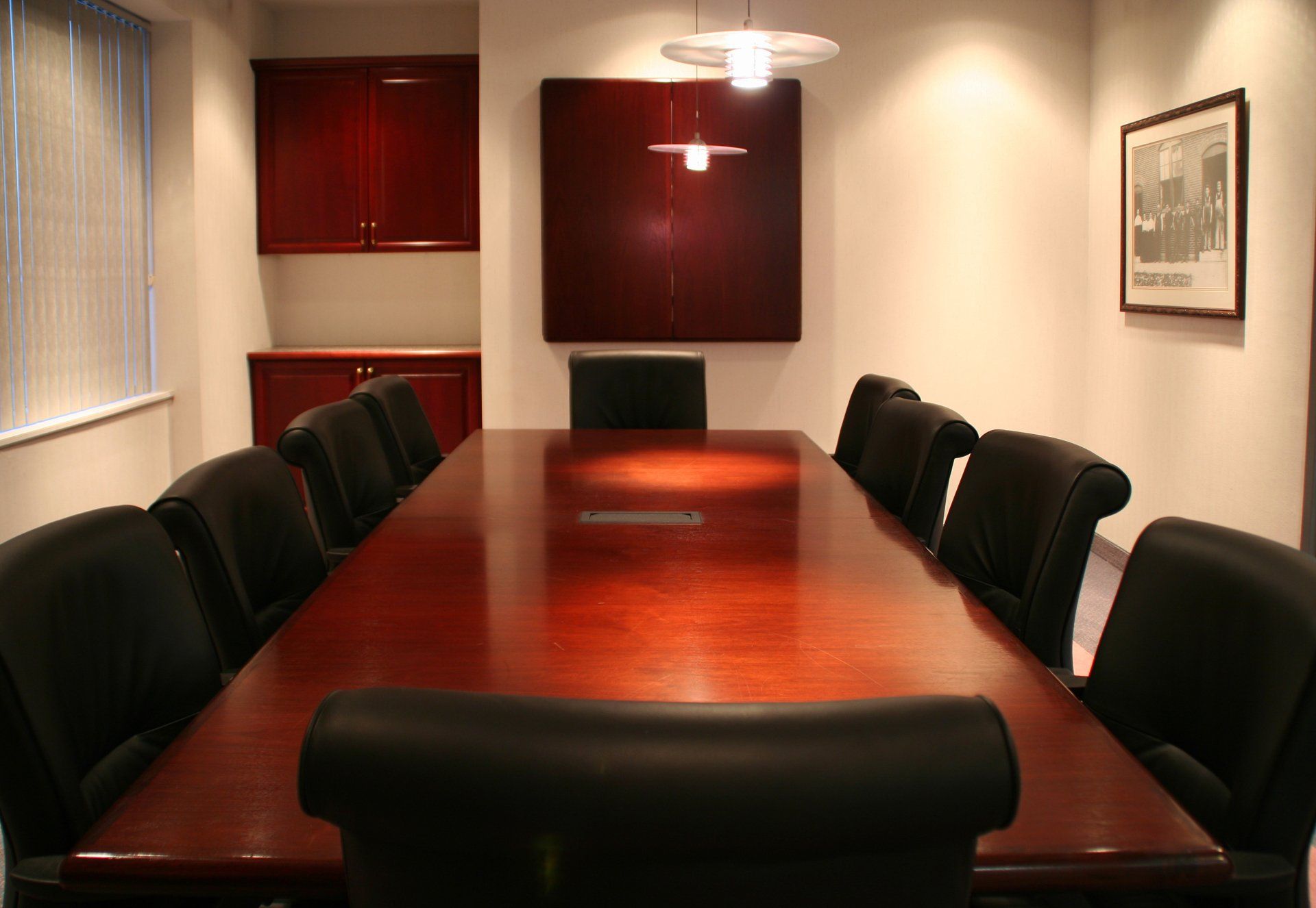 A conference room with a long wooden table and black chairs