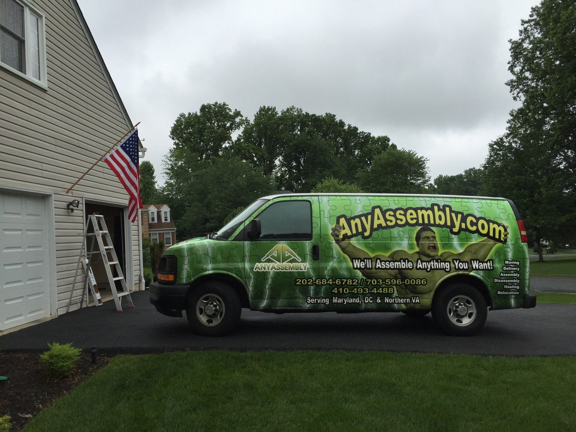A green van that says anyassembly.com is parked in front of a house