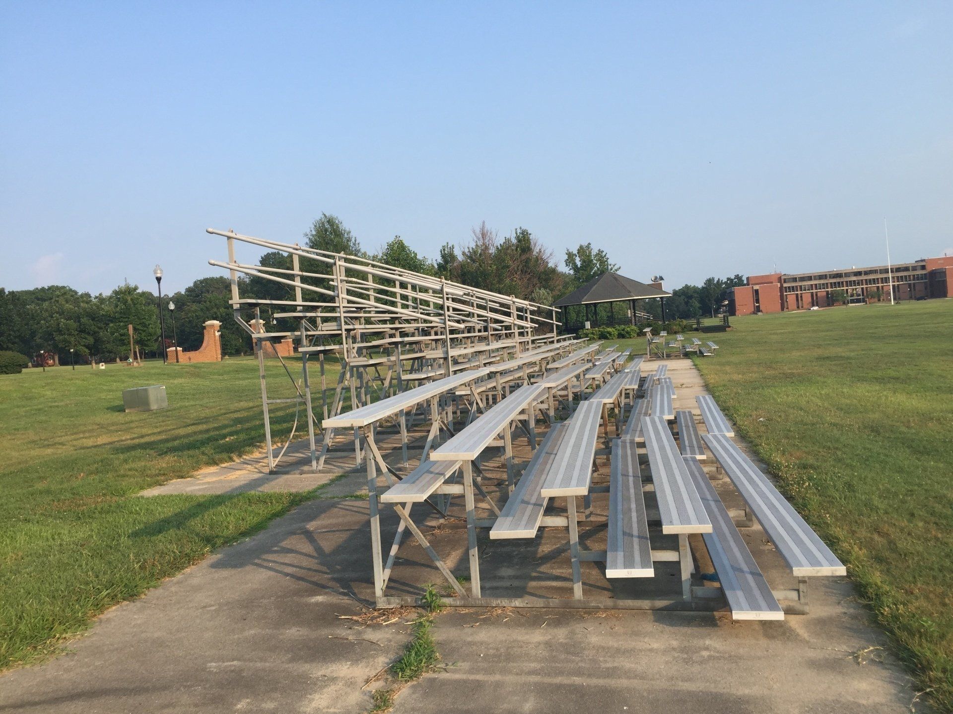 A row of bleachers in a field with a building in the background