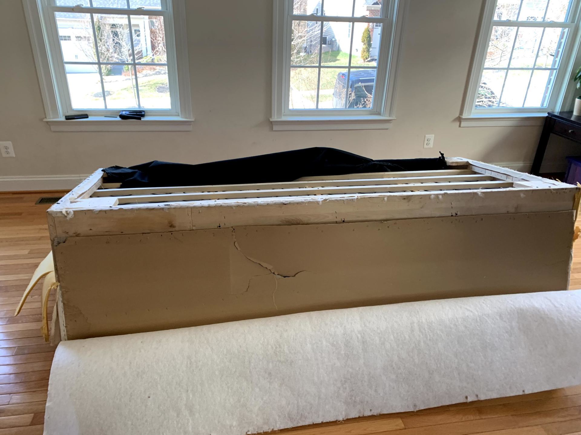 A cardboard box is sitting on top of a wooden floor in a living room.