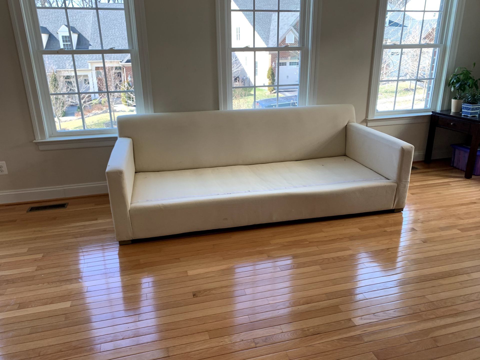 A white couch is sitting on a wooden floor in a living room.