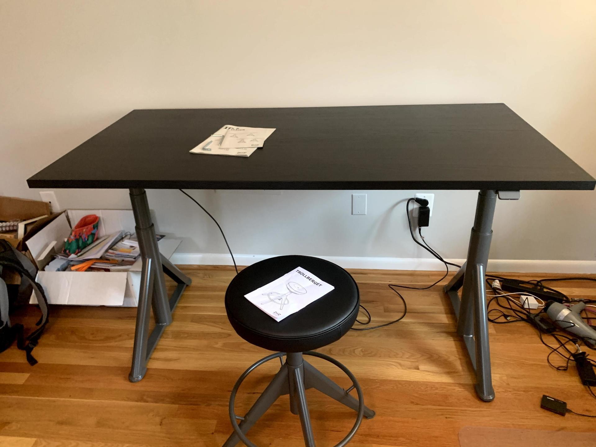 A black desk with a black stool in front of it