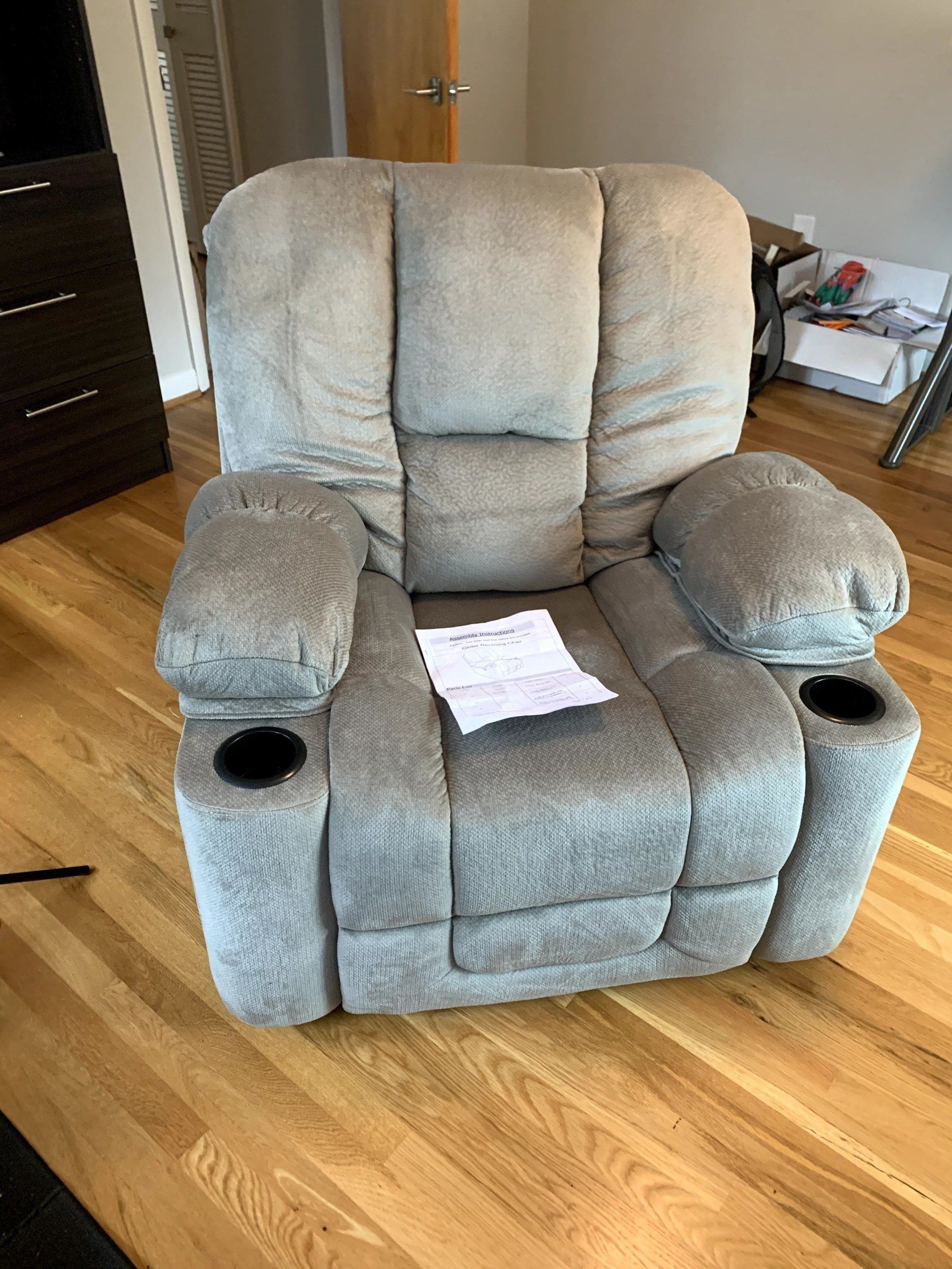 A recliner chair is sitting on a wooden floor in a living room.