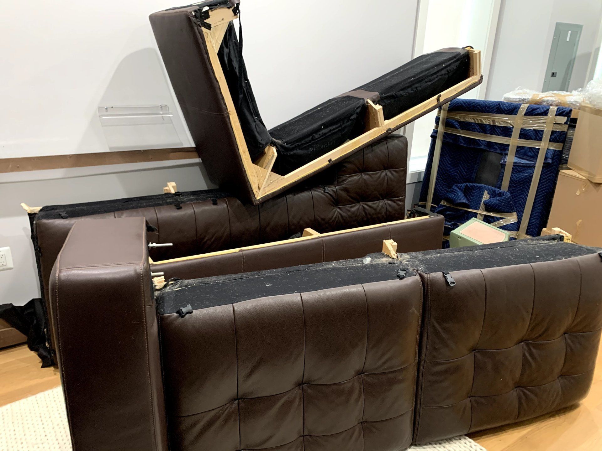 A brown leather couch is sitting on top of a wooden floor.