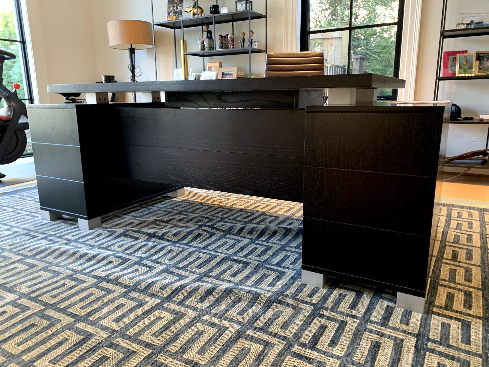A large black desk is sitting on top of a rug in a room.