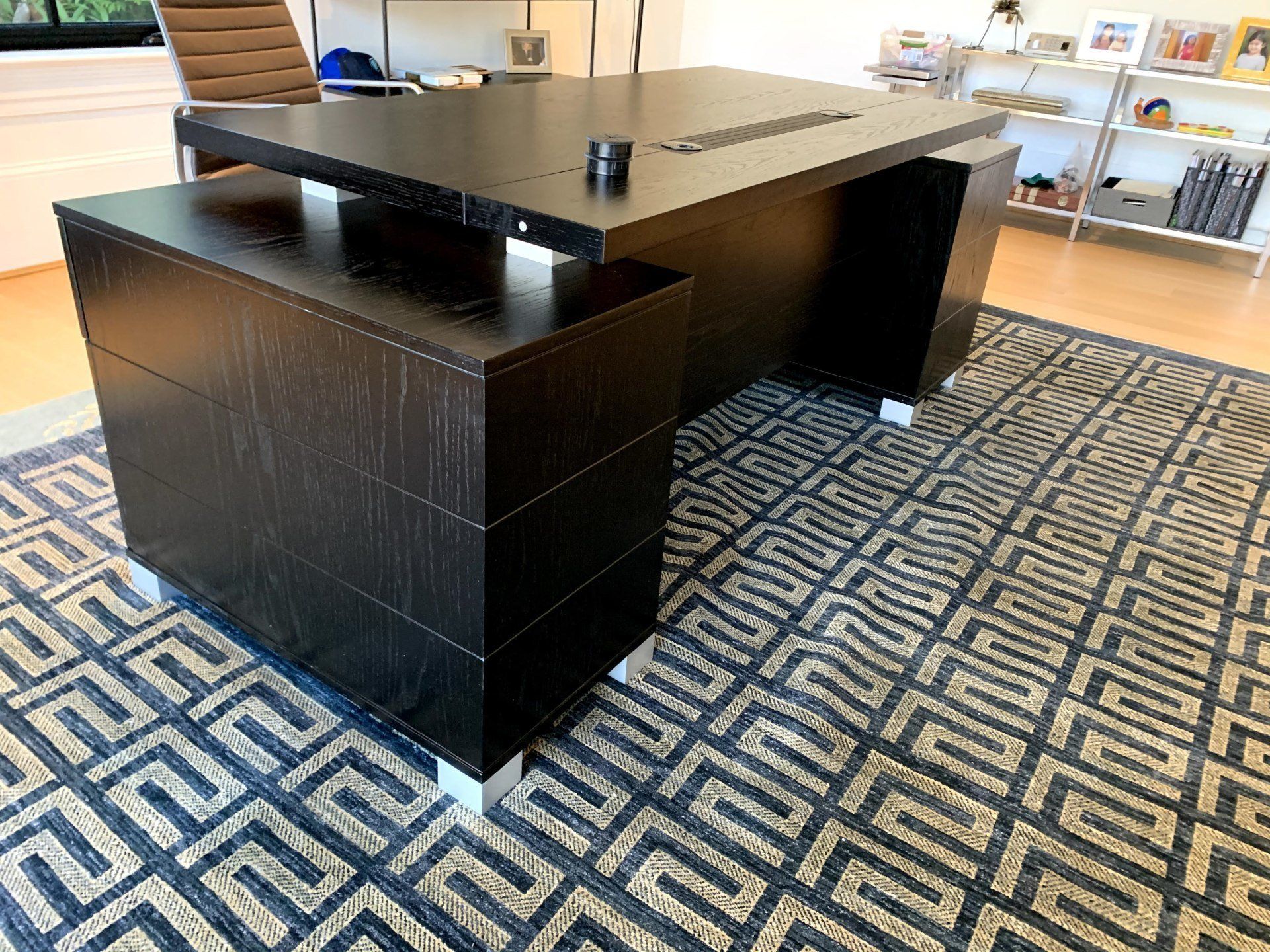 A black desk is sitting on top of a rug in a room.