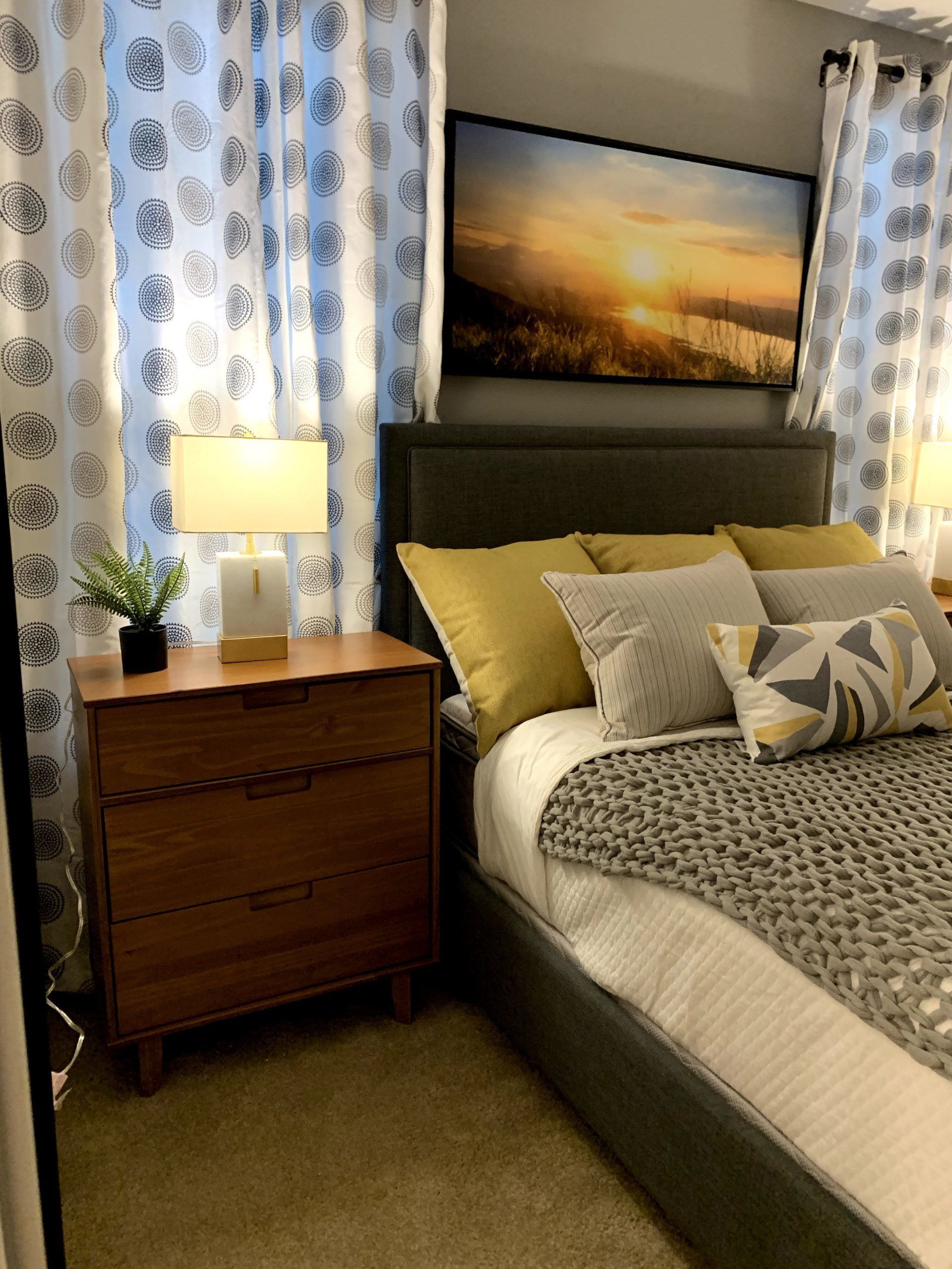 A bedroom with a large painting on the wall above the bed