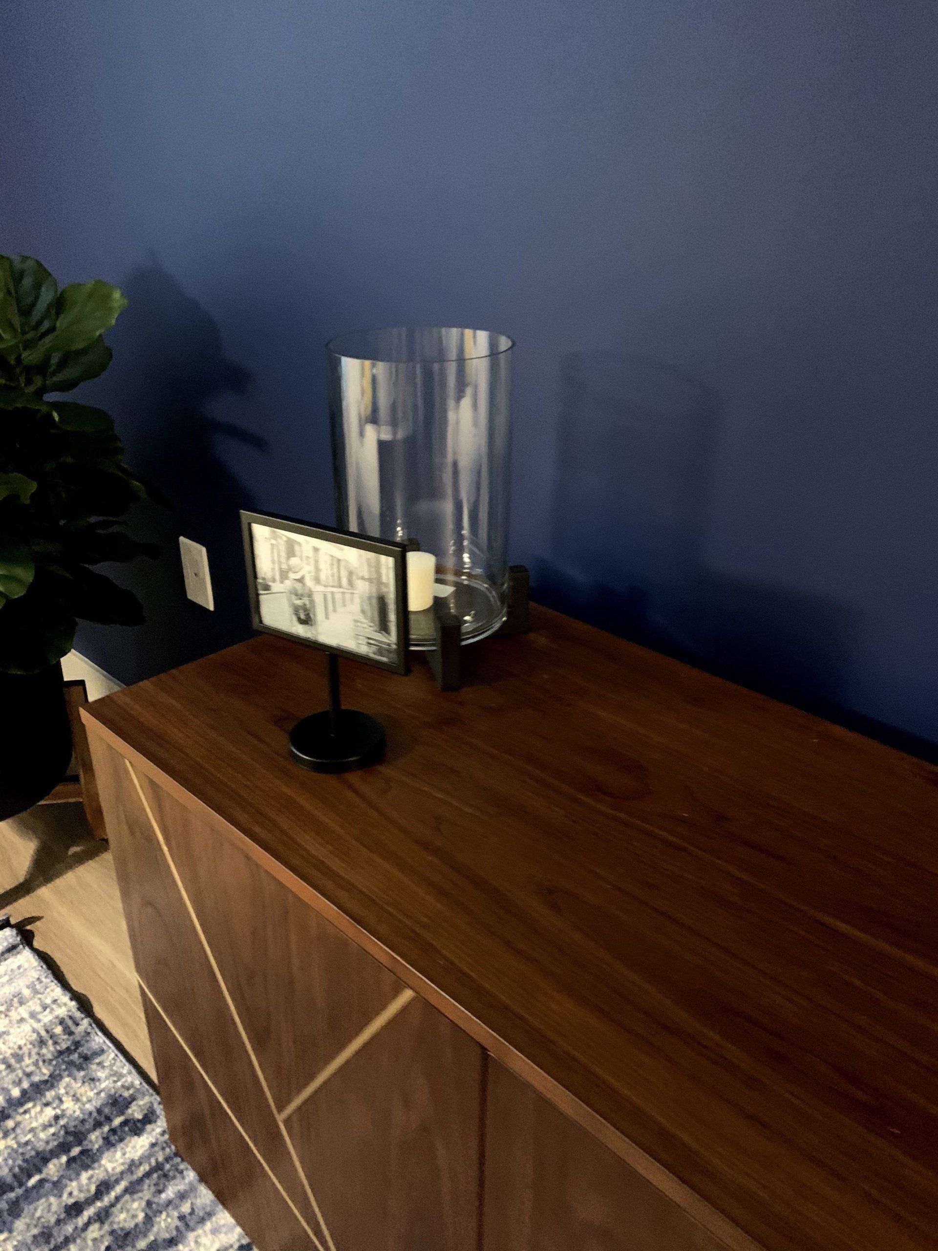 A picture frame is sitting on a wooden table next to a vase of candles.