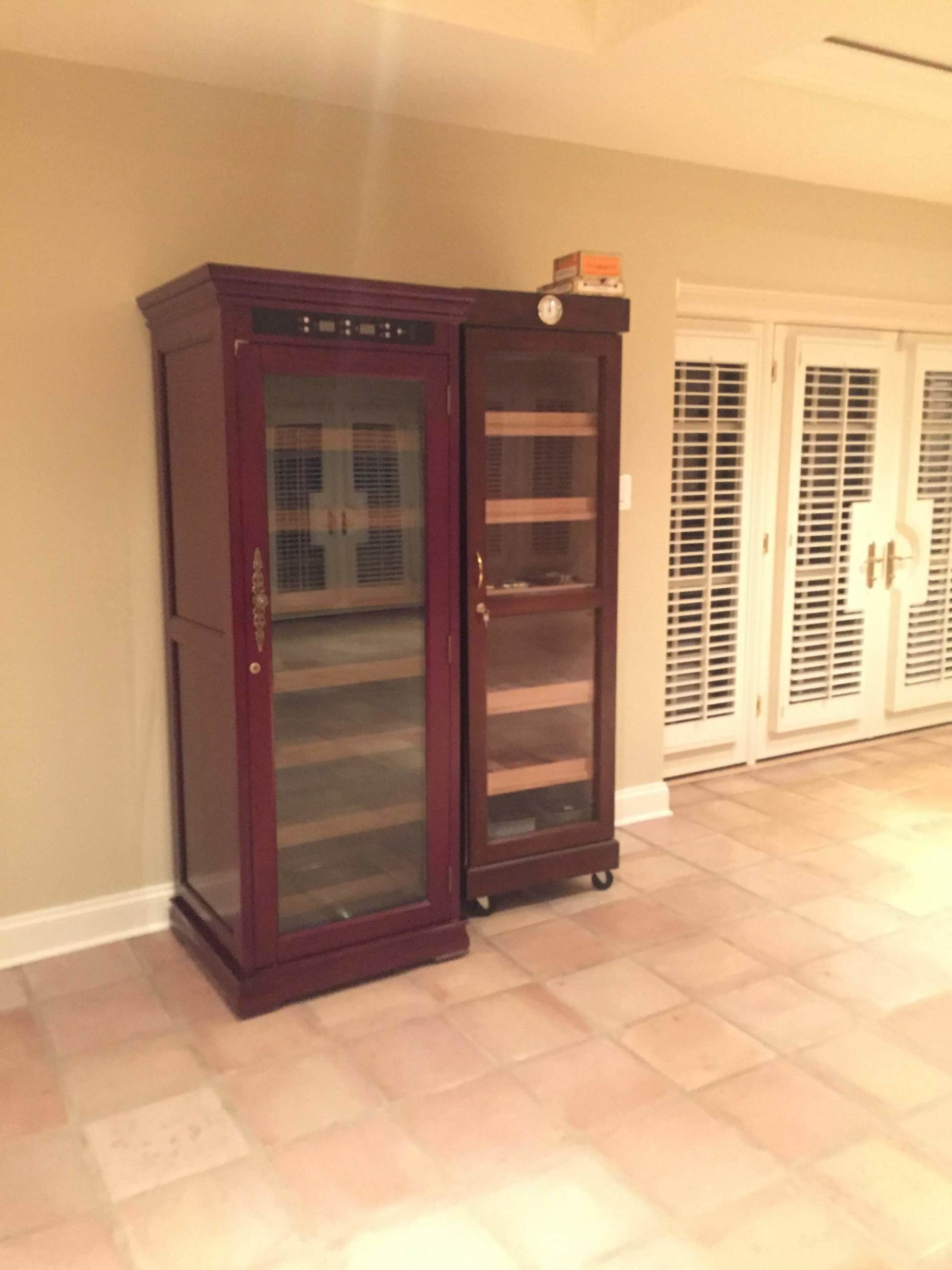 A wine cooler is sitting next to a cabinet in a room.