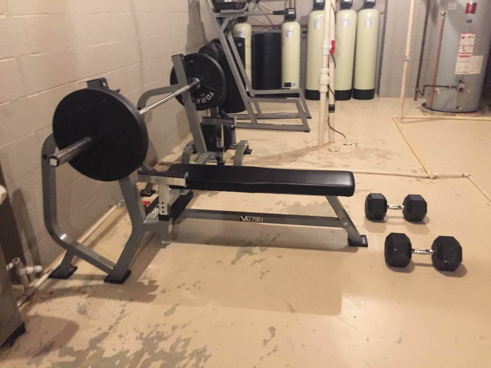 A gym with a bench and dumbbells on the floor