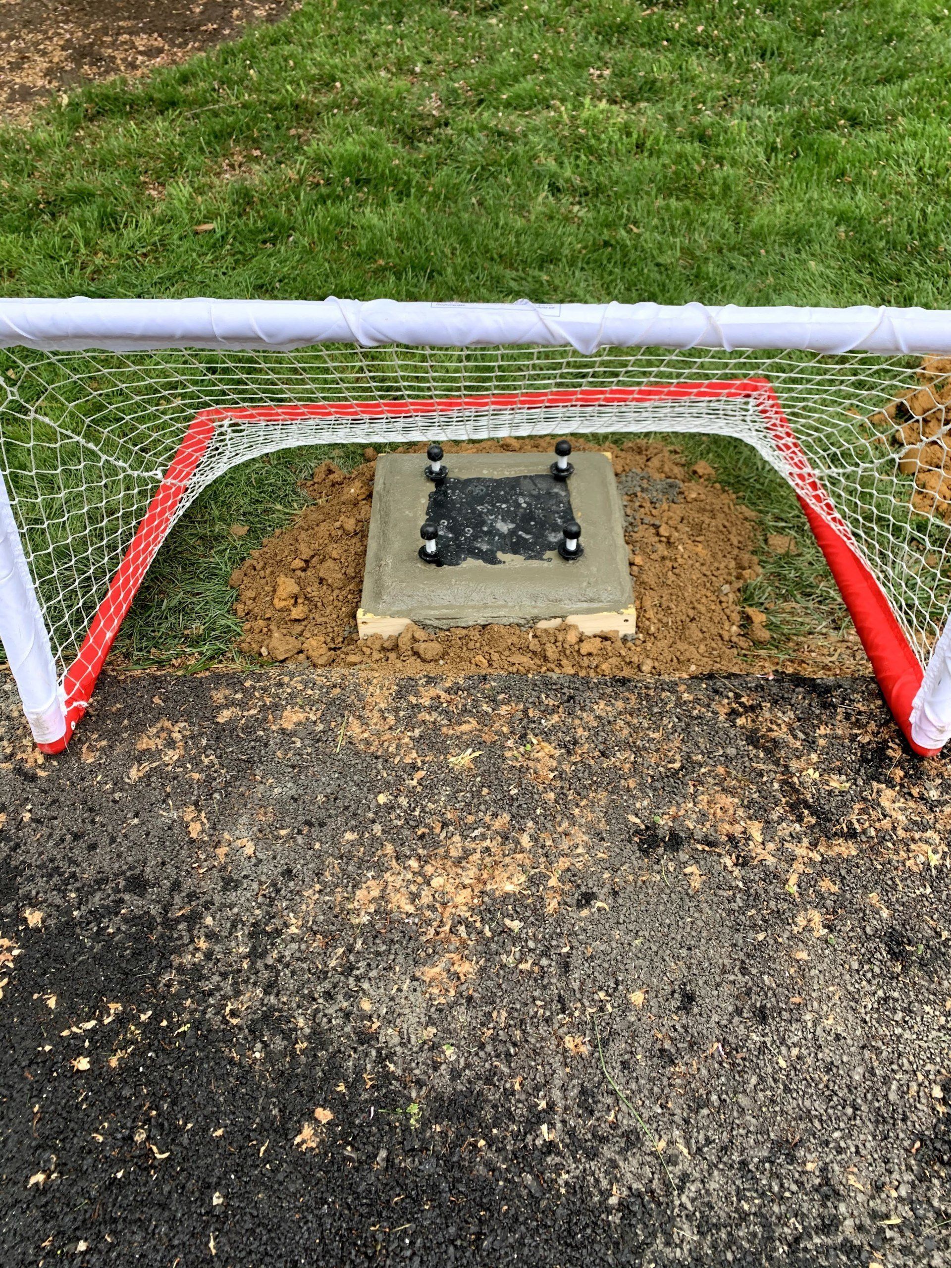 A soccer goal is sitting on top of a dirt field.