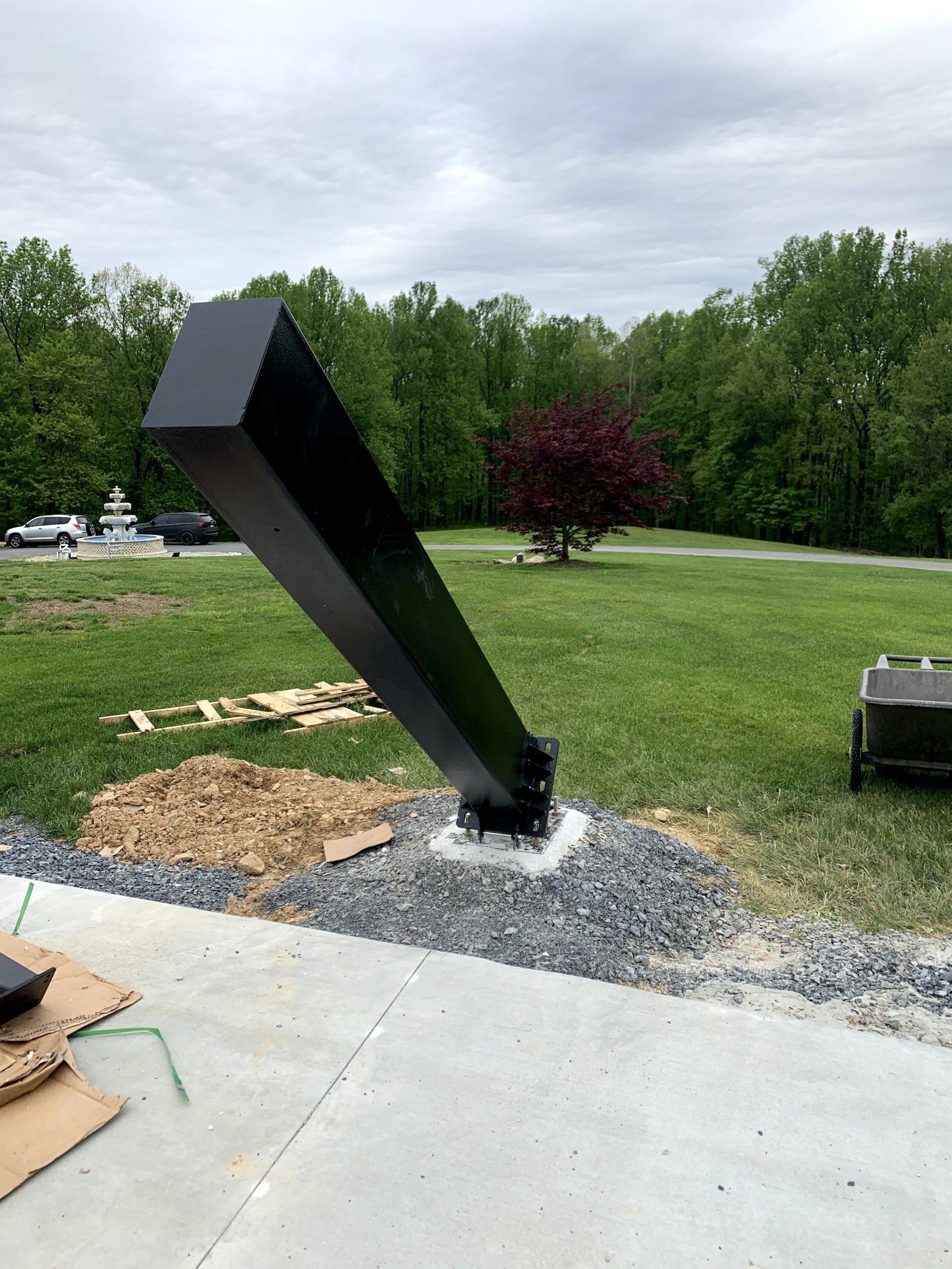 A large black pole is sitting in the middle of a grassy field.