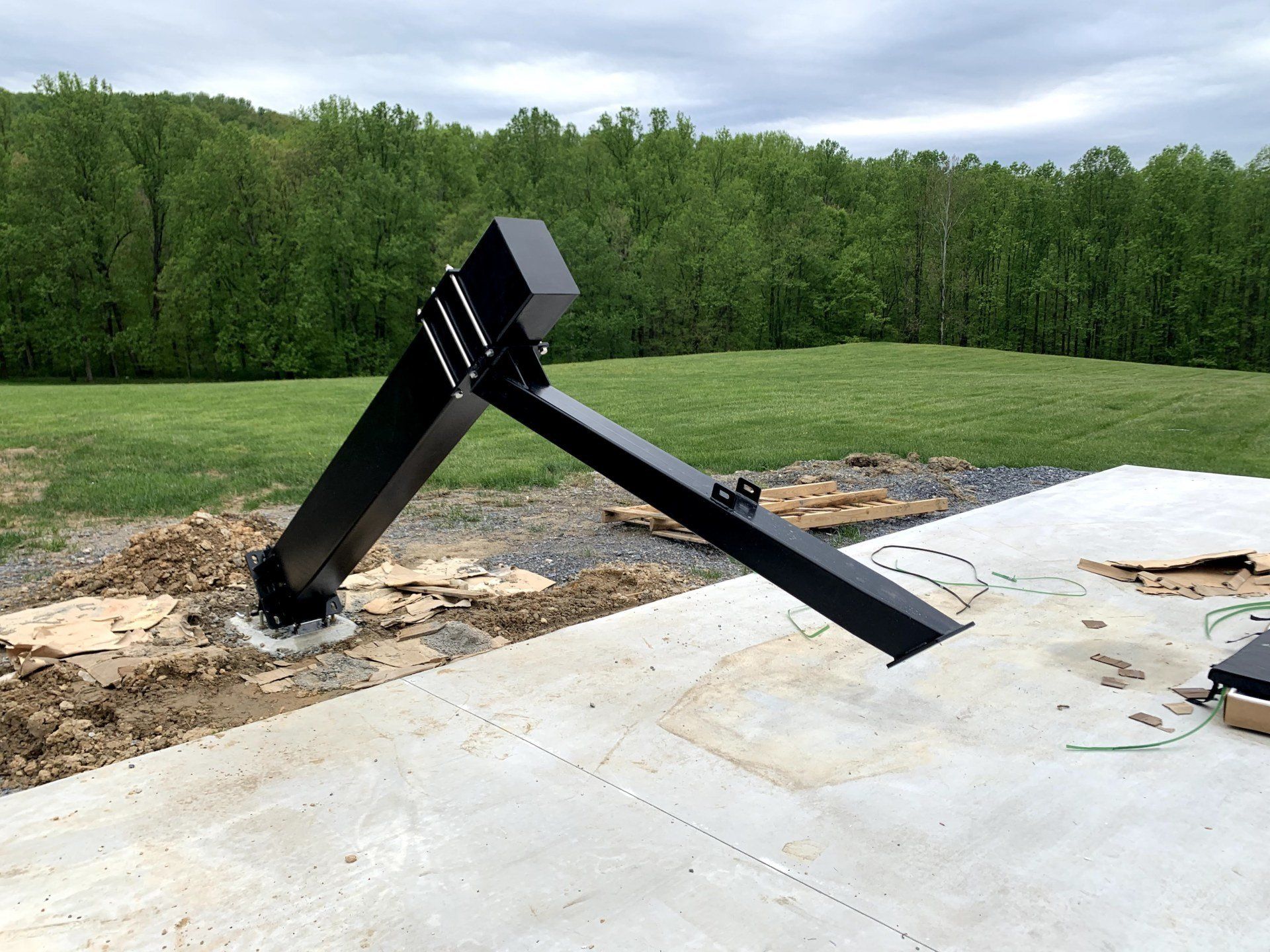 A black pole is sitting on a concrete surface in a field