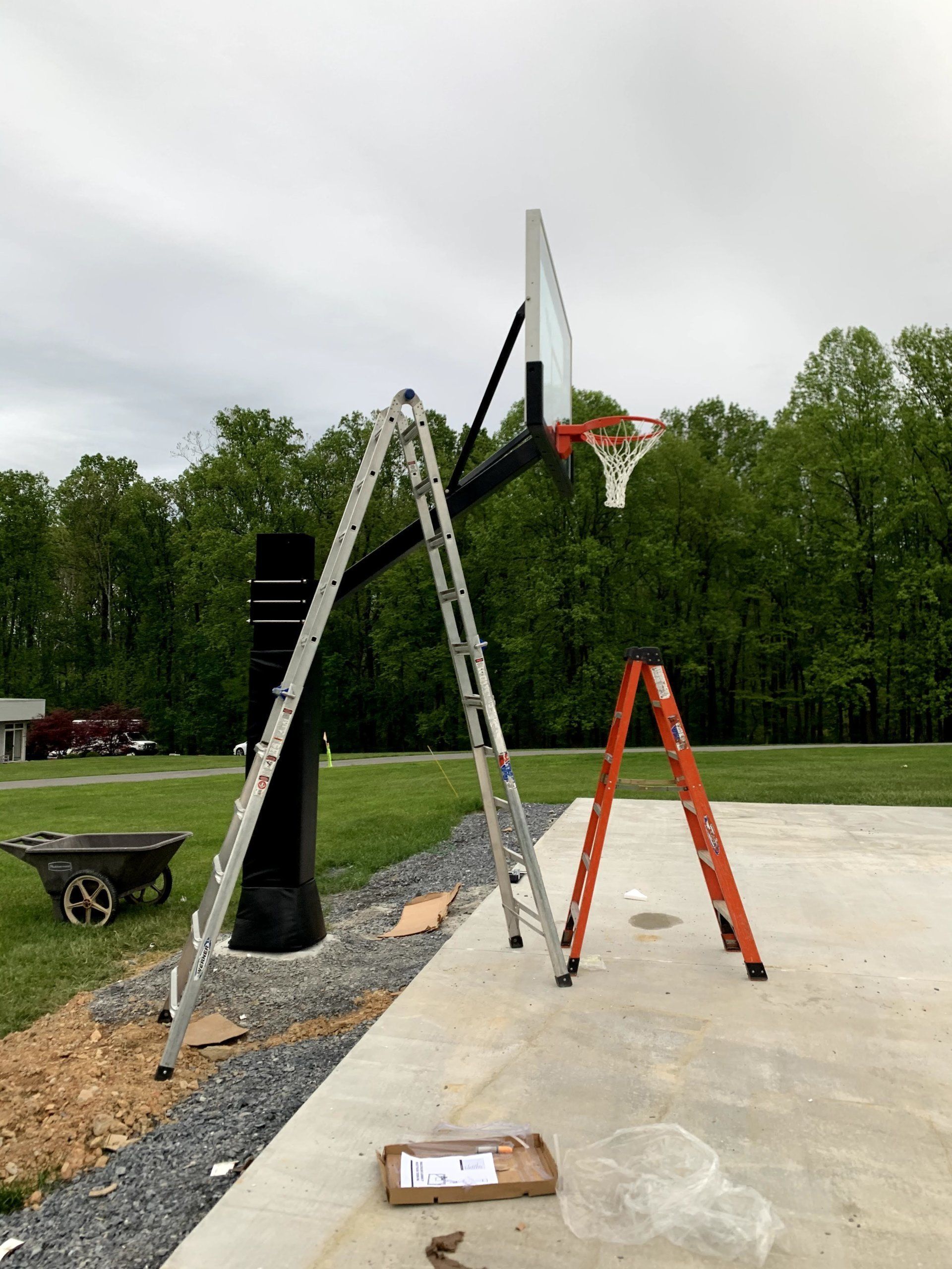 A ladder is sitting next to a basketball hoop.